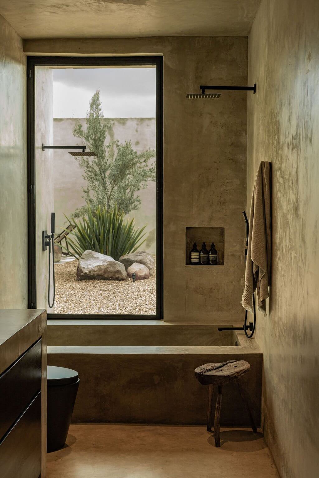 Villa ITO, Mexico — Concrete bathroom with open-air shower overlooking desert landscape, minimalist design with black fixtures and natural stone elements.