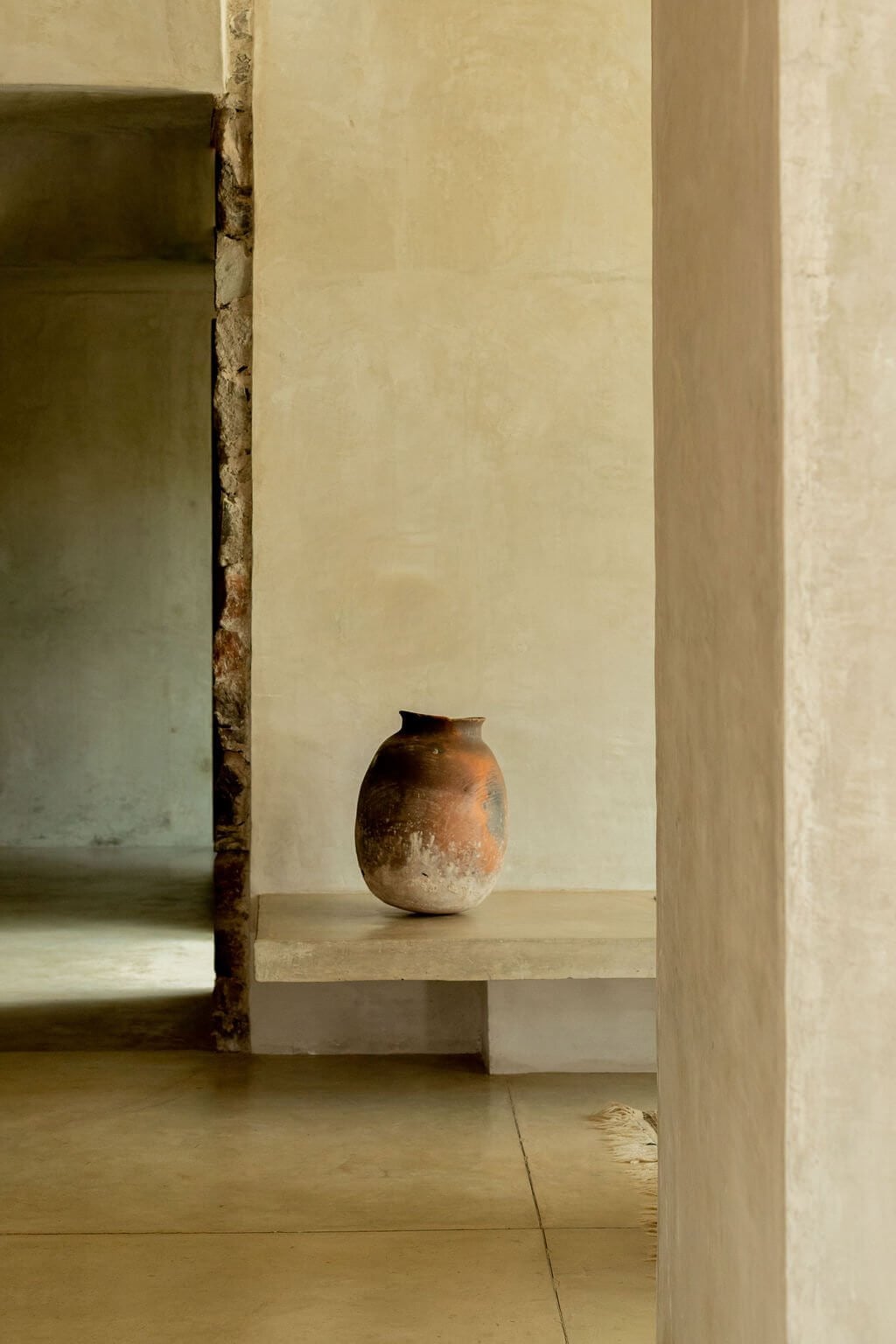 Villa ITO, Mexico — Terracotta vessel on stone ledge in minimalist hallway with natural light and austere architectural details.