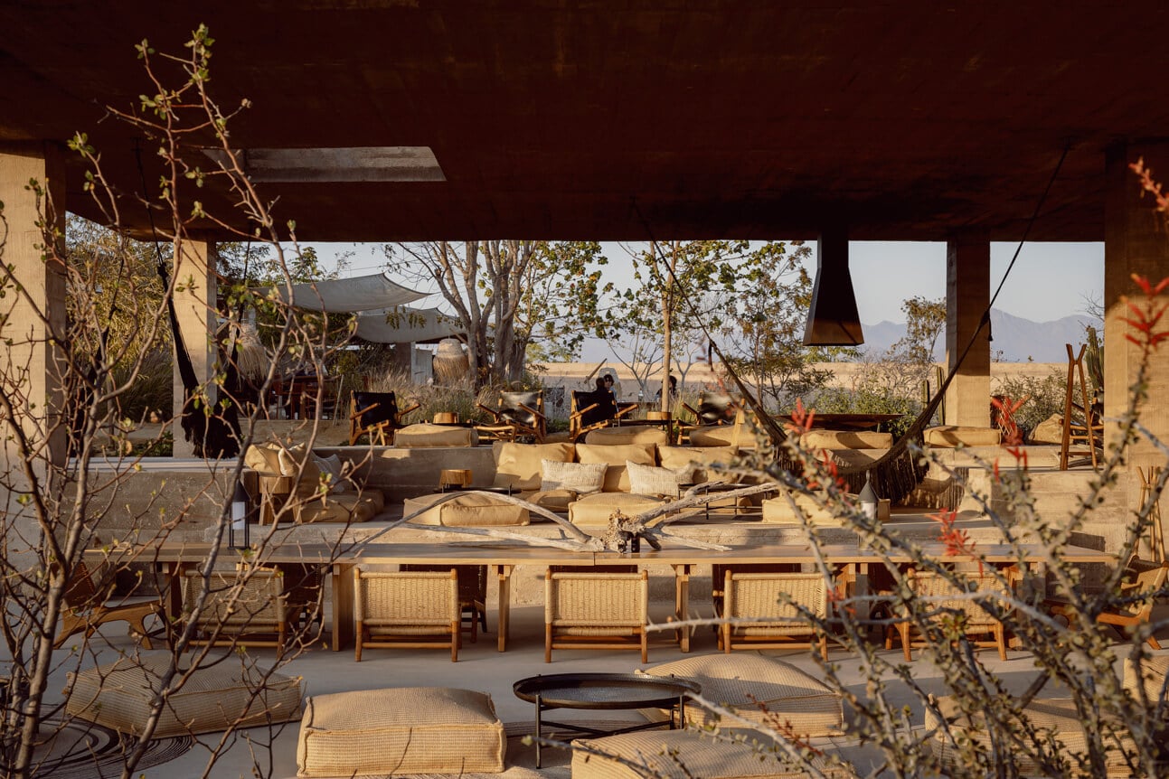 Paradero Todos Santos, Mexico — Open-air pavilion with woven chairs, earth-toned furnishings, desert landscape views, and natural light filtering through timber structure.
