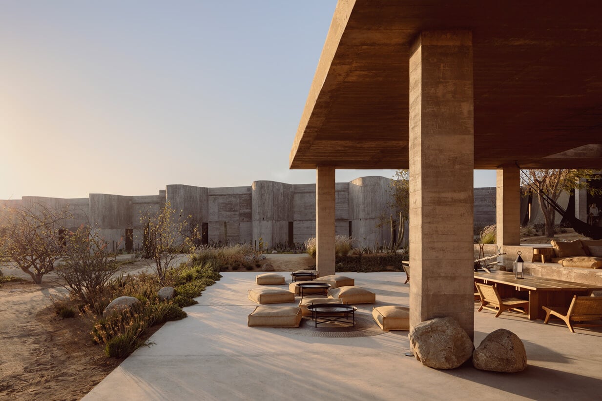 Paradero Todos Santos, Mexico — Concrete pavilion with timber ceiling, stone seating, desert landscaping, and minimalist architecture in golden hour light.
