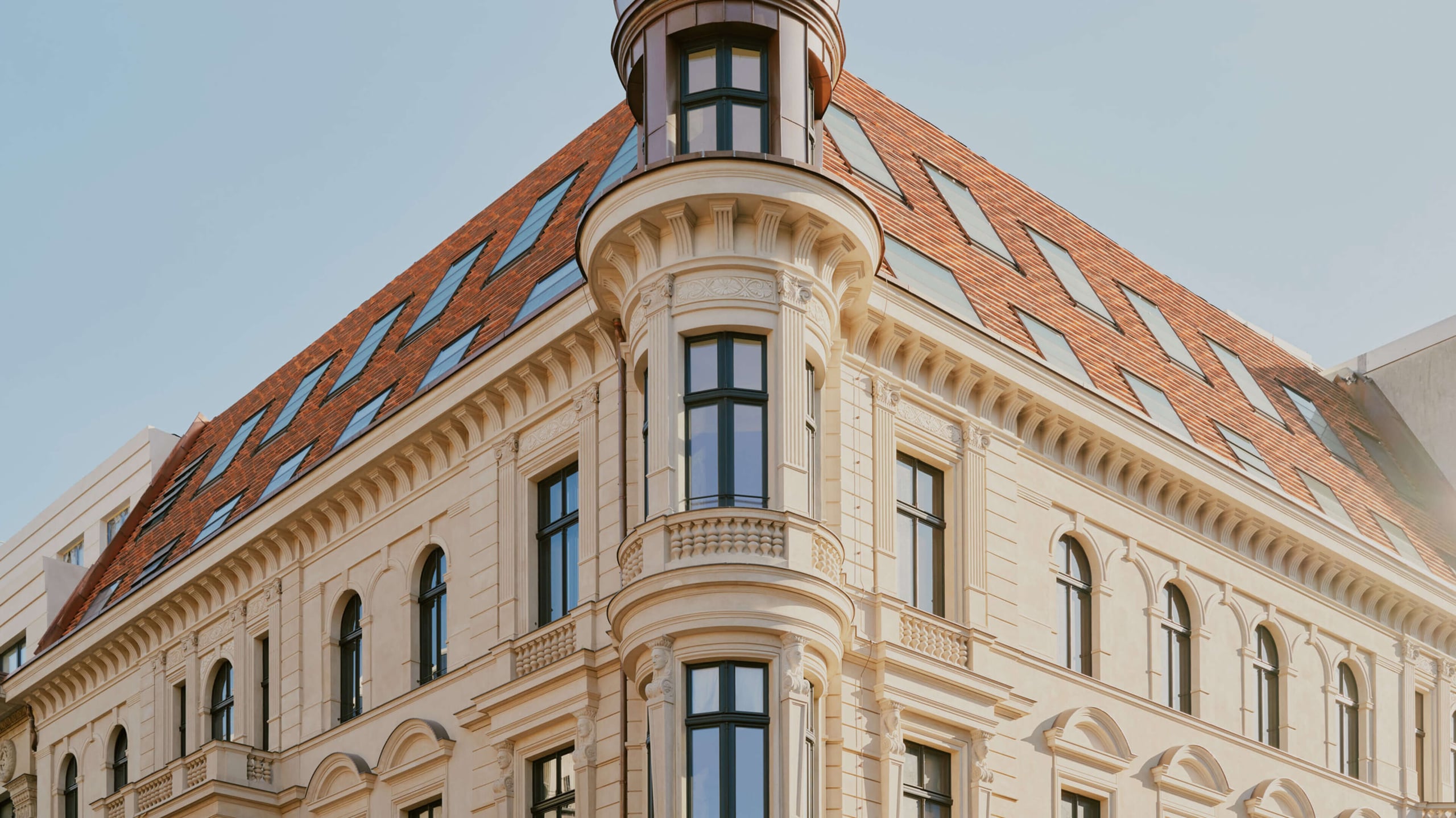 Château Royal, Europe — Cream neoclassical facade with ornamental detailing, arched windows, and copper mansard roof under clear sky.
