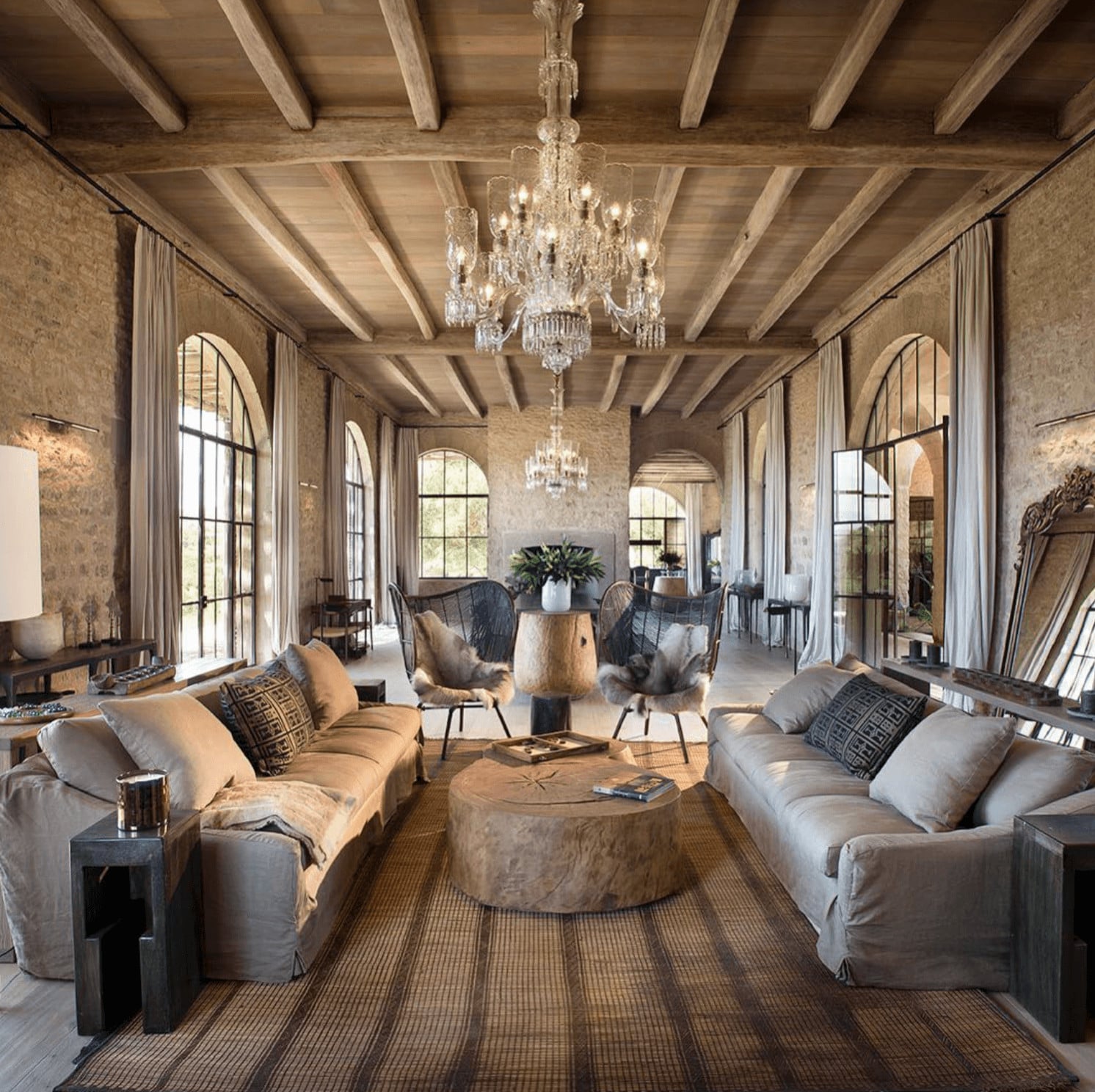 Arijiju Retreat, Africa — Soaring timber-beamed villa interior with crystal chandeliers, arched windows, neutral furnishings, and natural light across open living spaces.