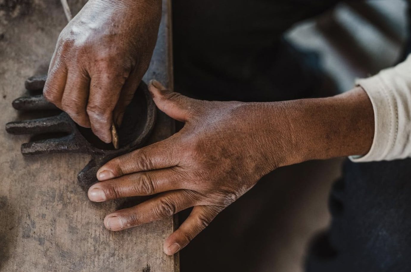 1050 Grados, Mexico — Hands placing wood in traditional clay oven, warm earthen tones and rustic cooking detail.
