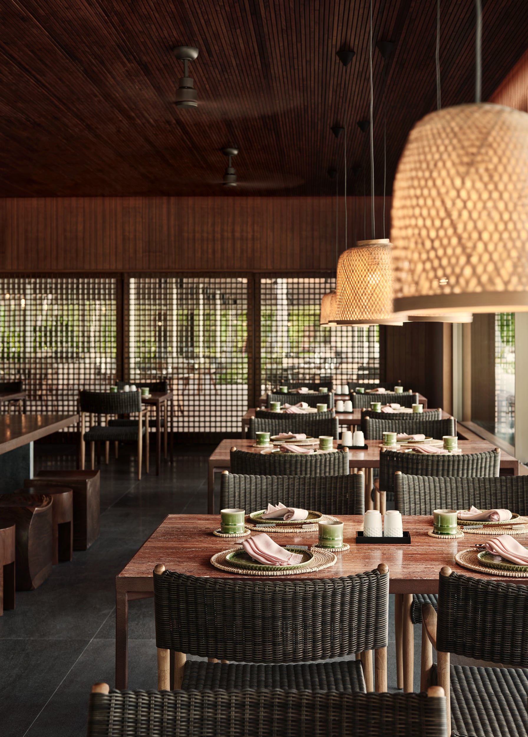 Patina Maldives, Asia — Woven rattan pendant lights and wicker dining chairs in modern restaurant with timber ceiling, geometric screens, and coastal views.