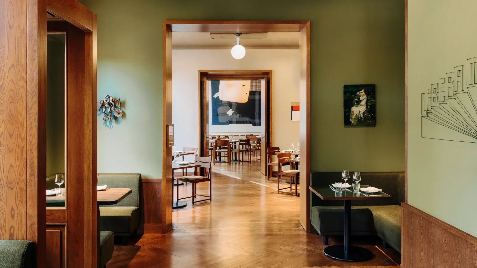 Château Royal, Europe — Mid-century modern dining room with walnut frames, sage green walls, polished wood floors, and gallery artwork.