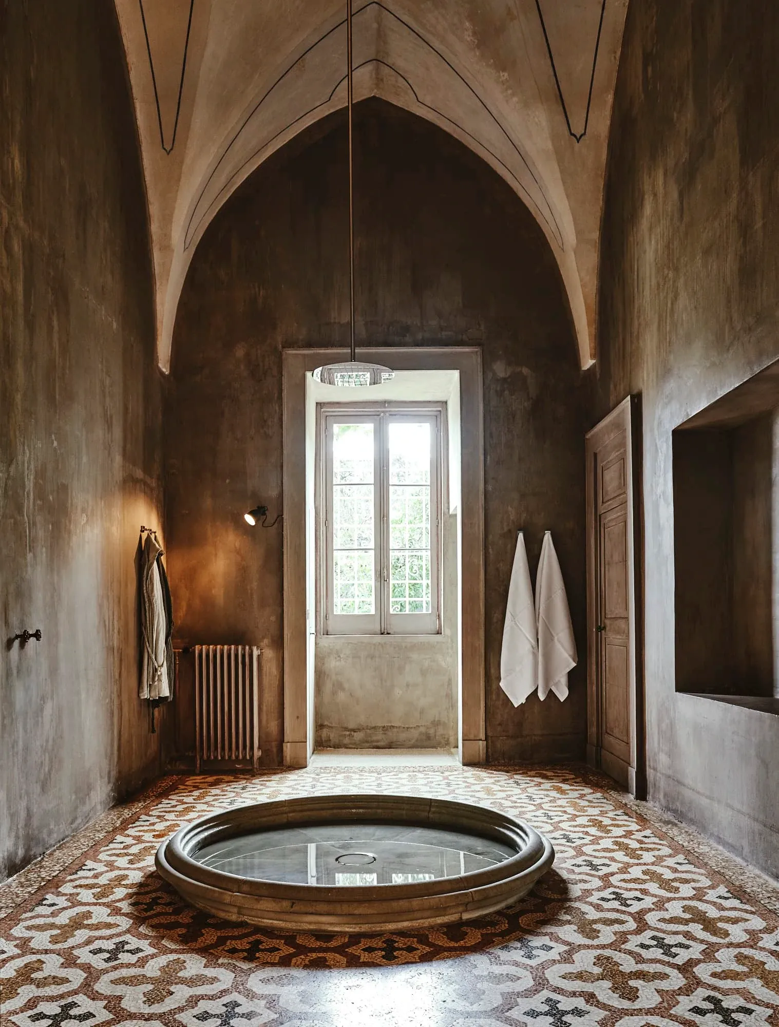 Palazzo Daniele, Europe — Sunlit spa with circular bathtub, vaulted brick ceiling, terracotta tile floor, classical architecture, minimal luxury interiors.