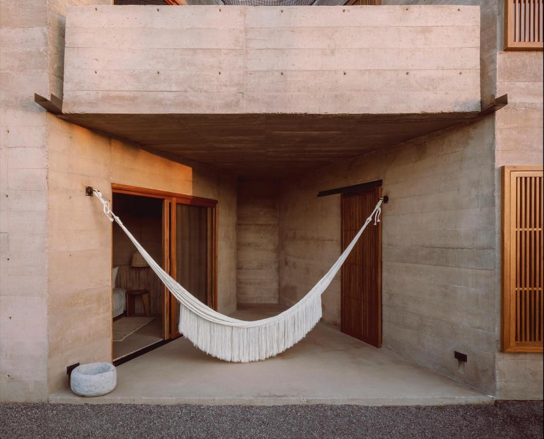 Paradero Todos Santos, Mexico — White fringe hammock suspended in minimalist concrete pavilion with wooden doors and natural light.