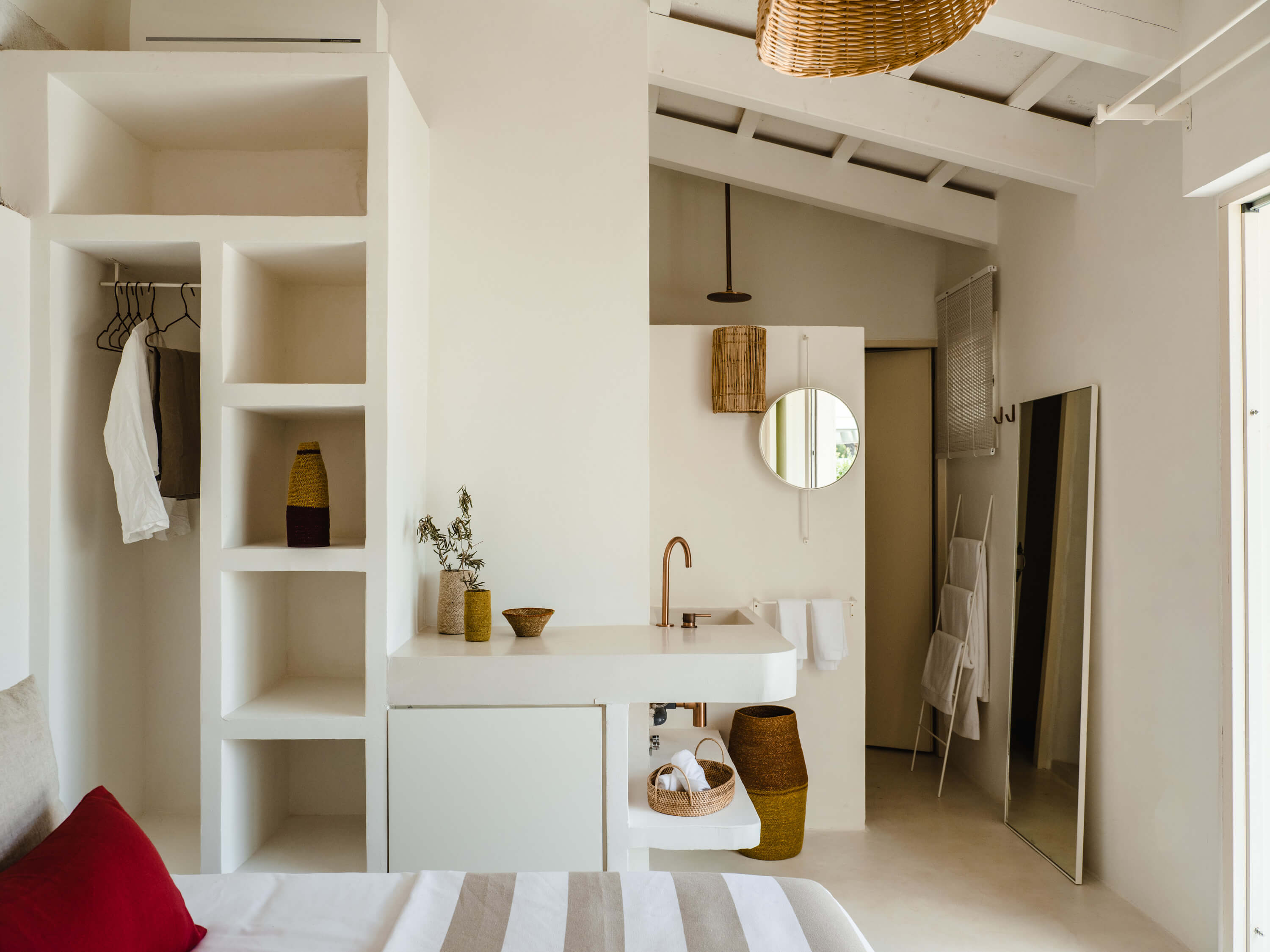 Morvedra Nou, Balearic Islands — Minimalist bathroom with white built-in shelving, marble sink, woven accents, and natural light from skylight.