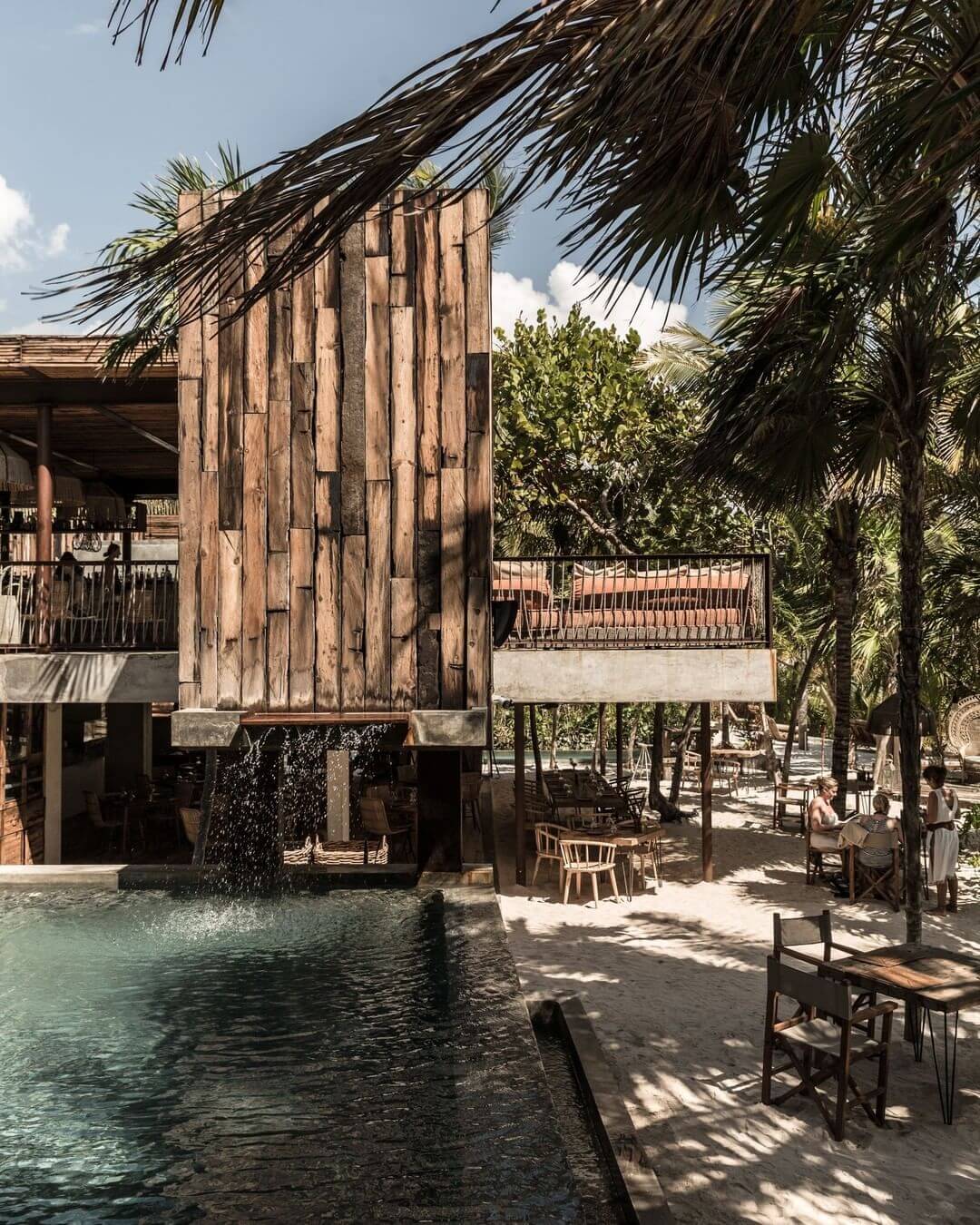 Be Tulum, Mexico — Wooden pavilion with palm thatch roof overlooking turquoise lagoon, minimalist furniture, tropical beachfront architecture.