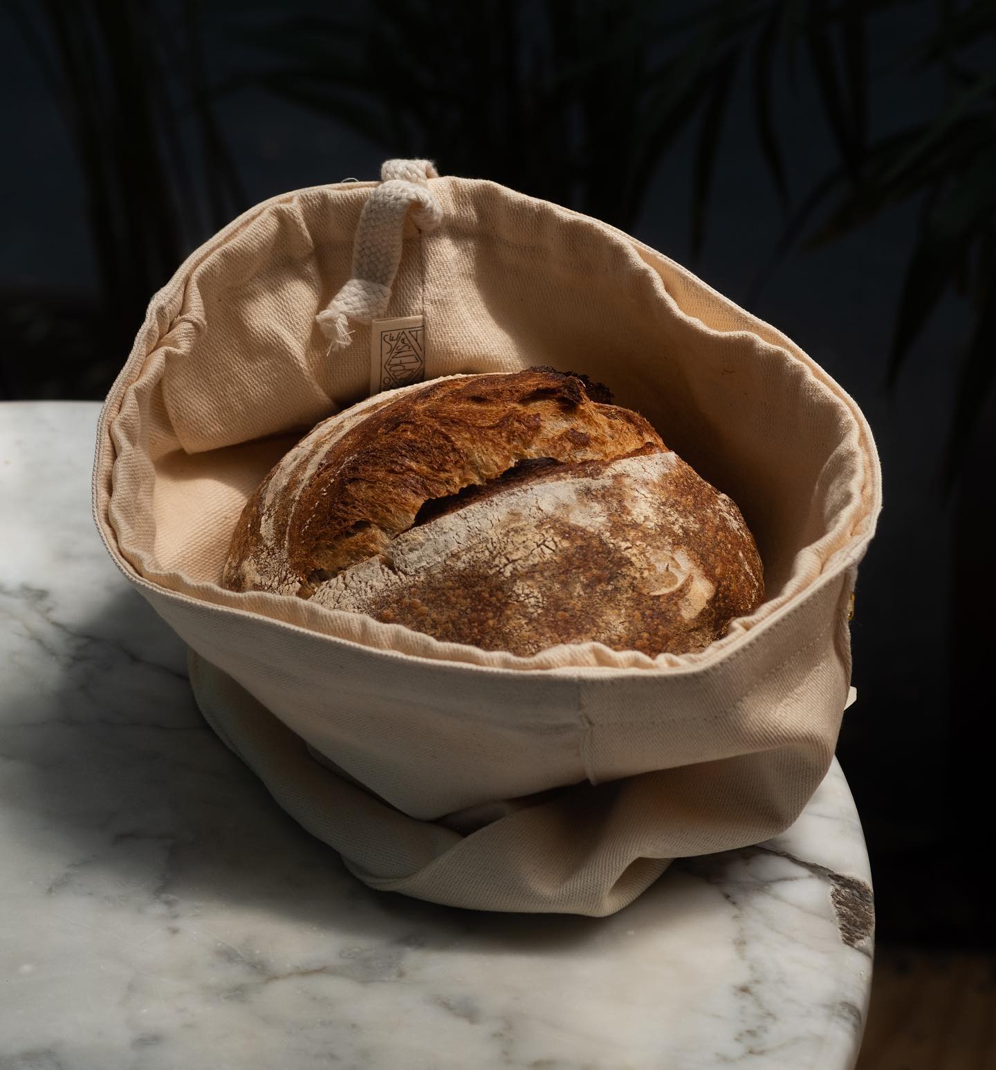 Panadería Rosetta, Mexico City, Mexico — artisanal sourdough loaf in cream linen bread basket on marble surface, warm natural light, luxury hospitality styling.