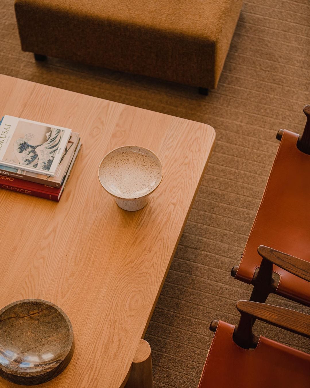 Aethos Ericeira, Portugal — Minimalist wooden table with ceramic vessels and design books, warm natural light, contemporary hospitality interior.