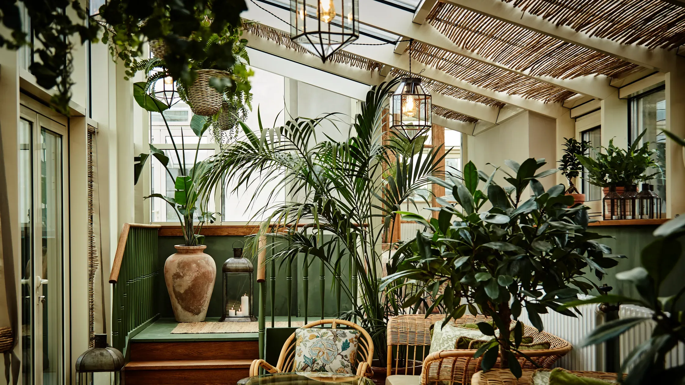 Hotel Sanders, Copenhagen, Denmark — Plant-filled conservatory with green wainscoting, wooden beams, rattan furniture, and natural light from large windows.