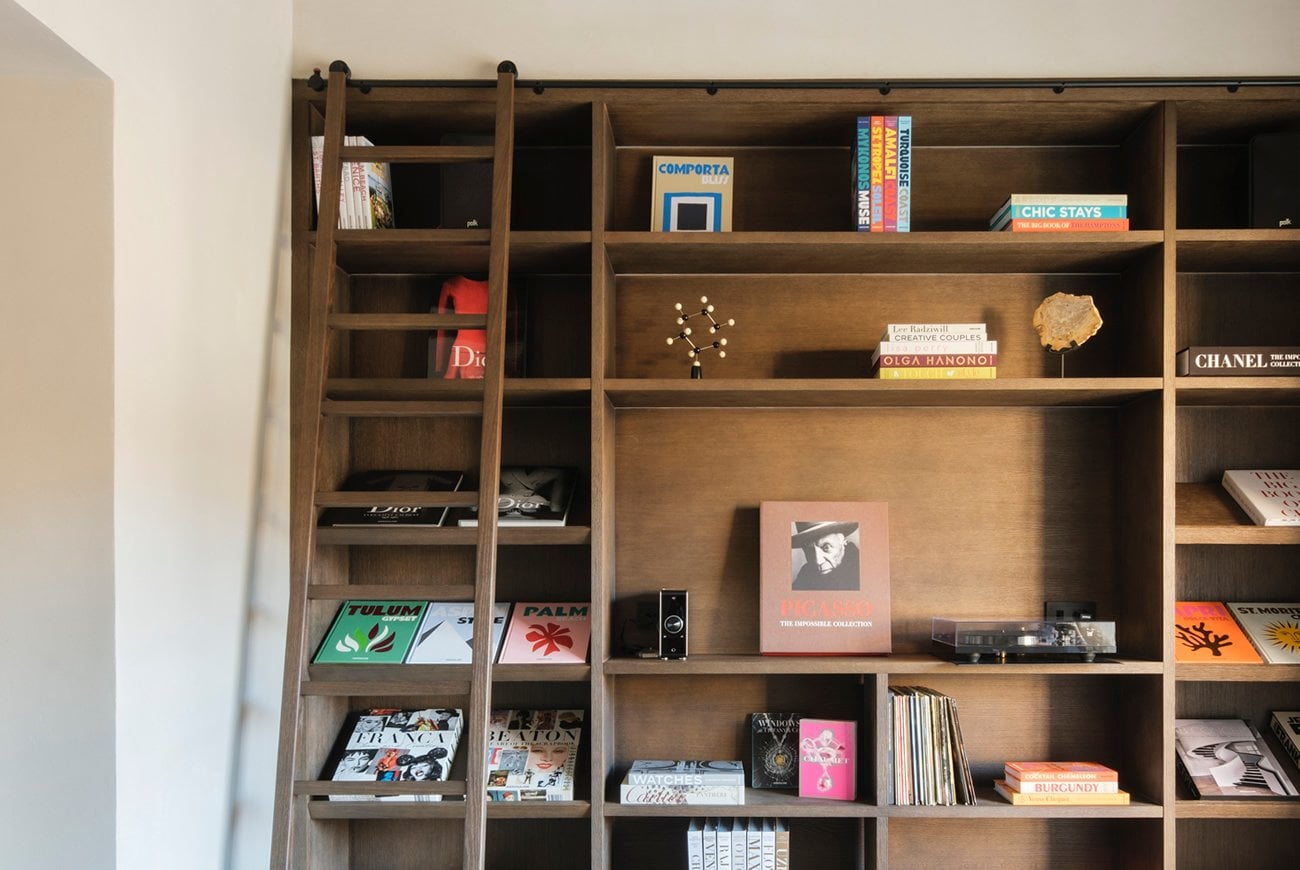 Can Ferrereta, Balearic Islands, Spain — Wooden shelving unit displaying design books, art objects, and curated luxury lifestyle items in warm natural light.