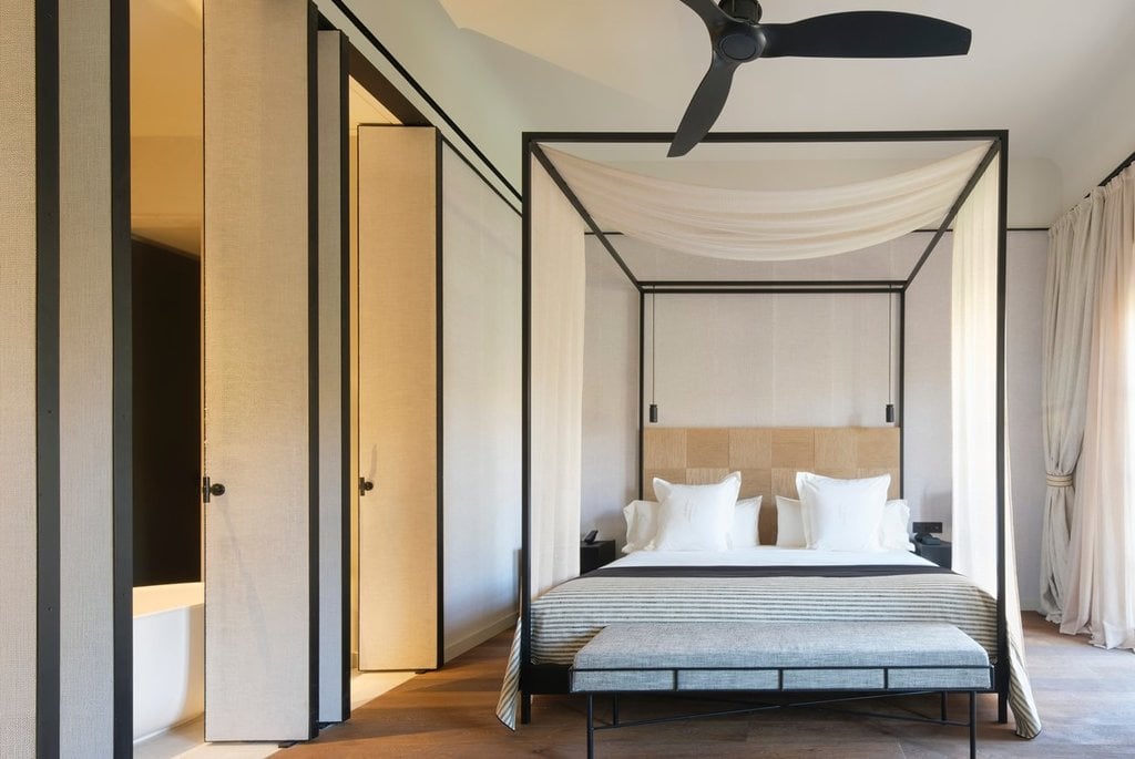 Can Ferrereta, Balearic Islands, Spain — Modern canopy bed with linen drapes in minimalist bedroom with black steel frame, warm wood tones, and natural light.