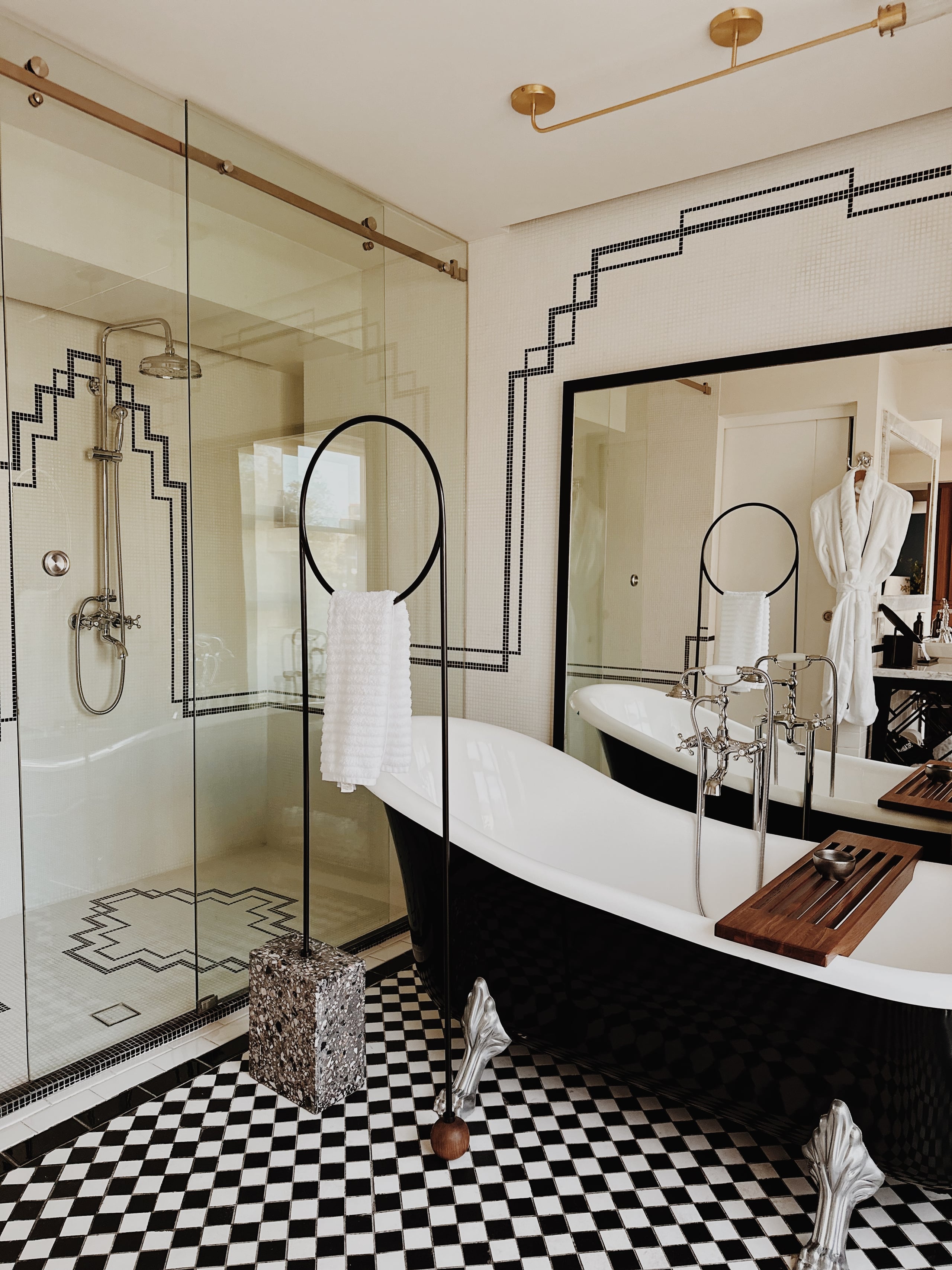Campos Polanco, Mexico — Luxury bathroom with black-and-white tile flooring, freestanding soaking tub, walk-in shower, brass fixtures, and geometric tile border detailing.