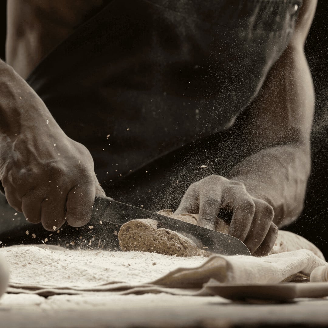 Gaia — Artisan baker's hands dusting flour across dough with dramatic backlighting, capturing traditional bread-making craft and culinary expertise near Gaia, Europe.