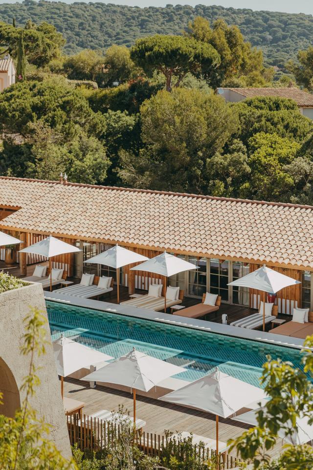 Lily of the Valley, Europe — Poolside terracotta lounge with white umbrellas overlooking forested hills, modern architecture and Mediterranean design.