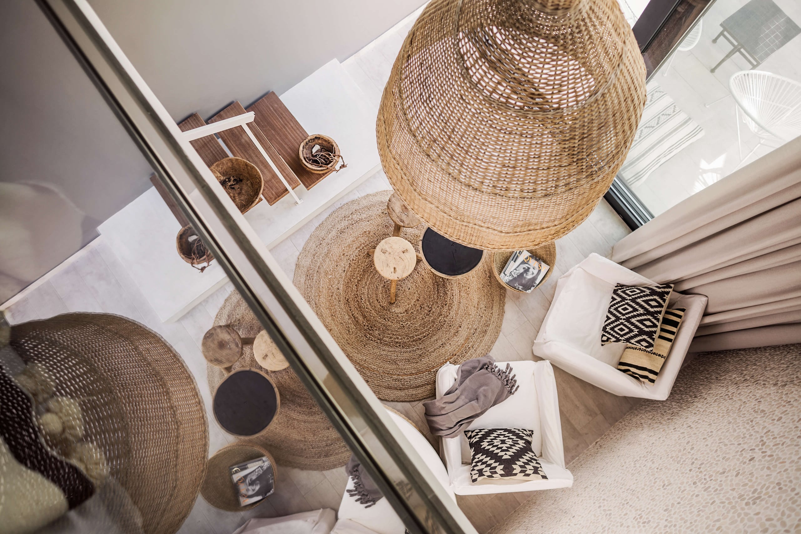 Casa Cook Rhodes, Europe — overhead view of natural fiber baskets, jute rug, and monochromatic textiles arranged on white surfaces in minimalist hospitality interior.