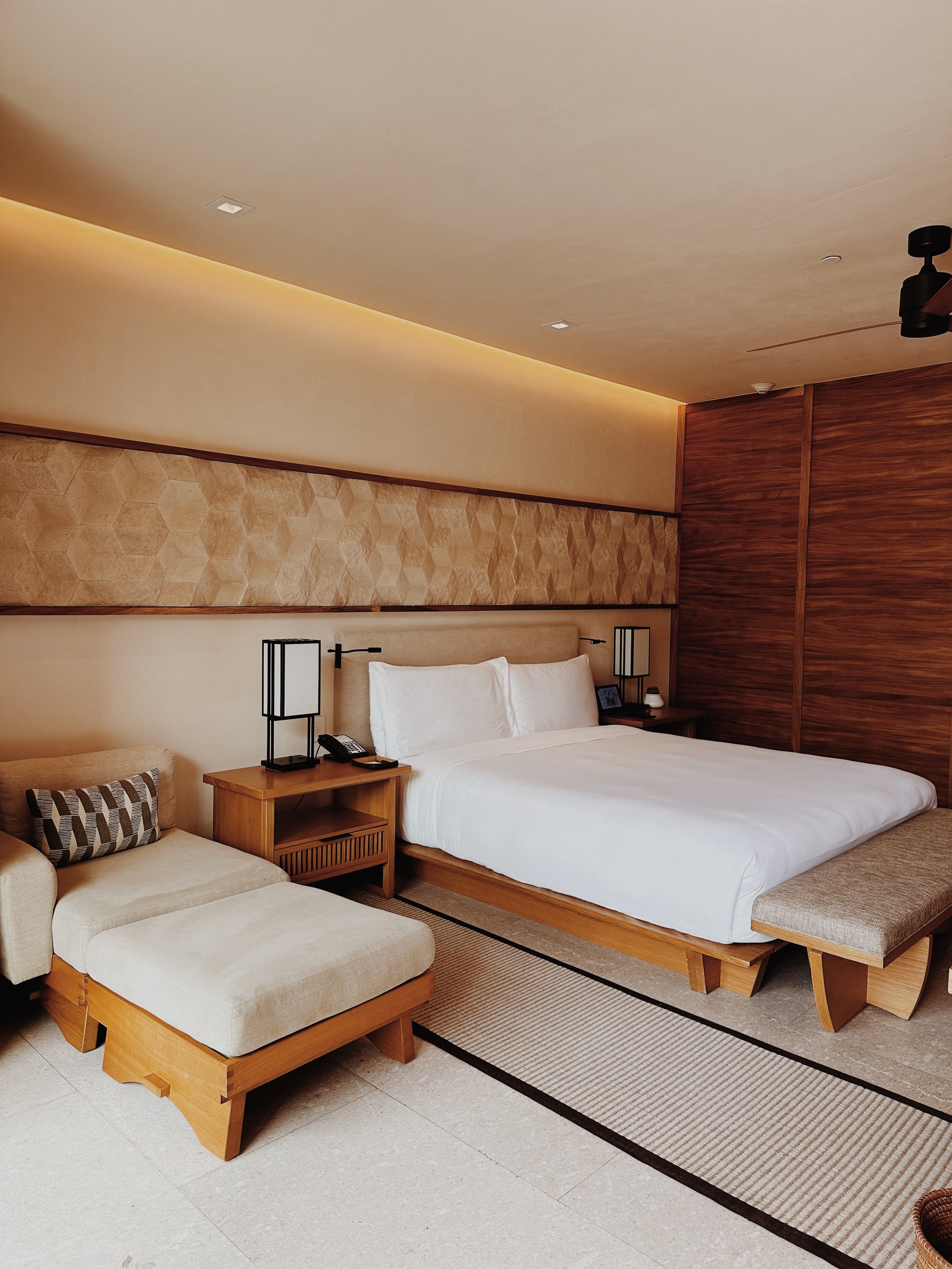 Nobu Los Cabos, Mexico — Modern bedroom with warm wood furnishings, neutral upholstery, ambient ceiling lights, and minimalist Japanese-inspired design aesthetic.