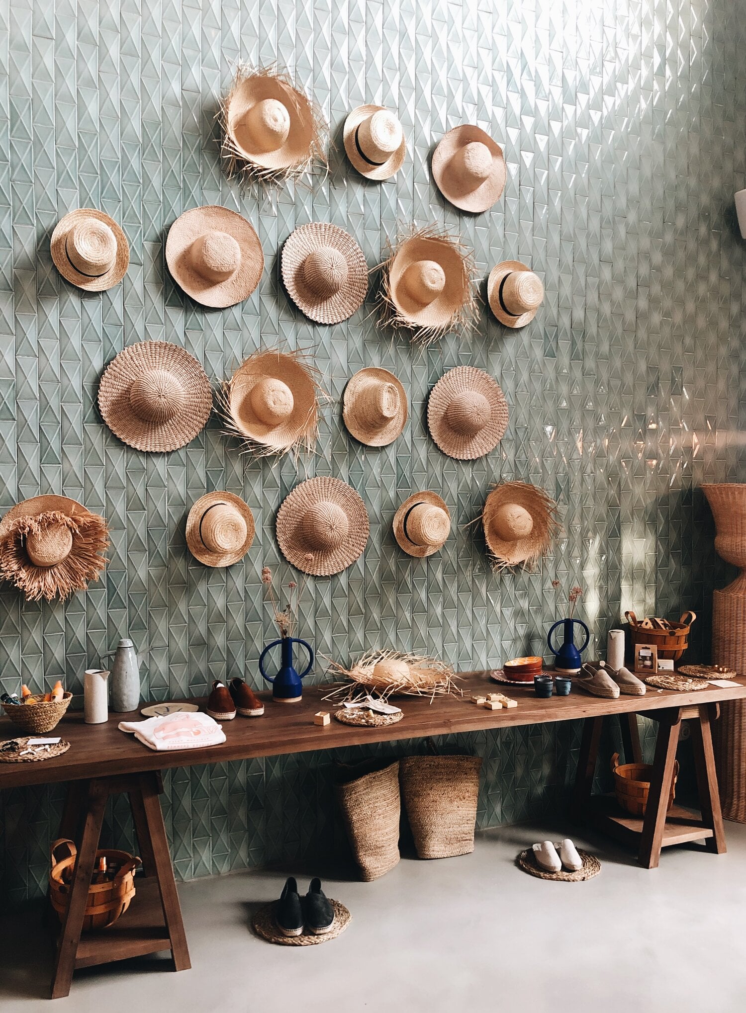 Menorca Experimental, Balearic Islands, Spain — Woven straw hats arranged on textured wall above wooden workbench with natural light and artisanal craft materials.