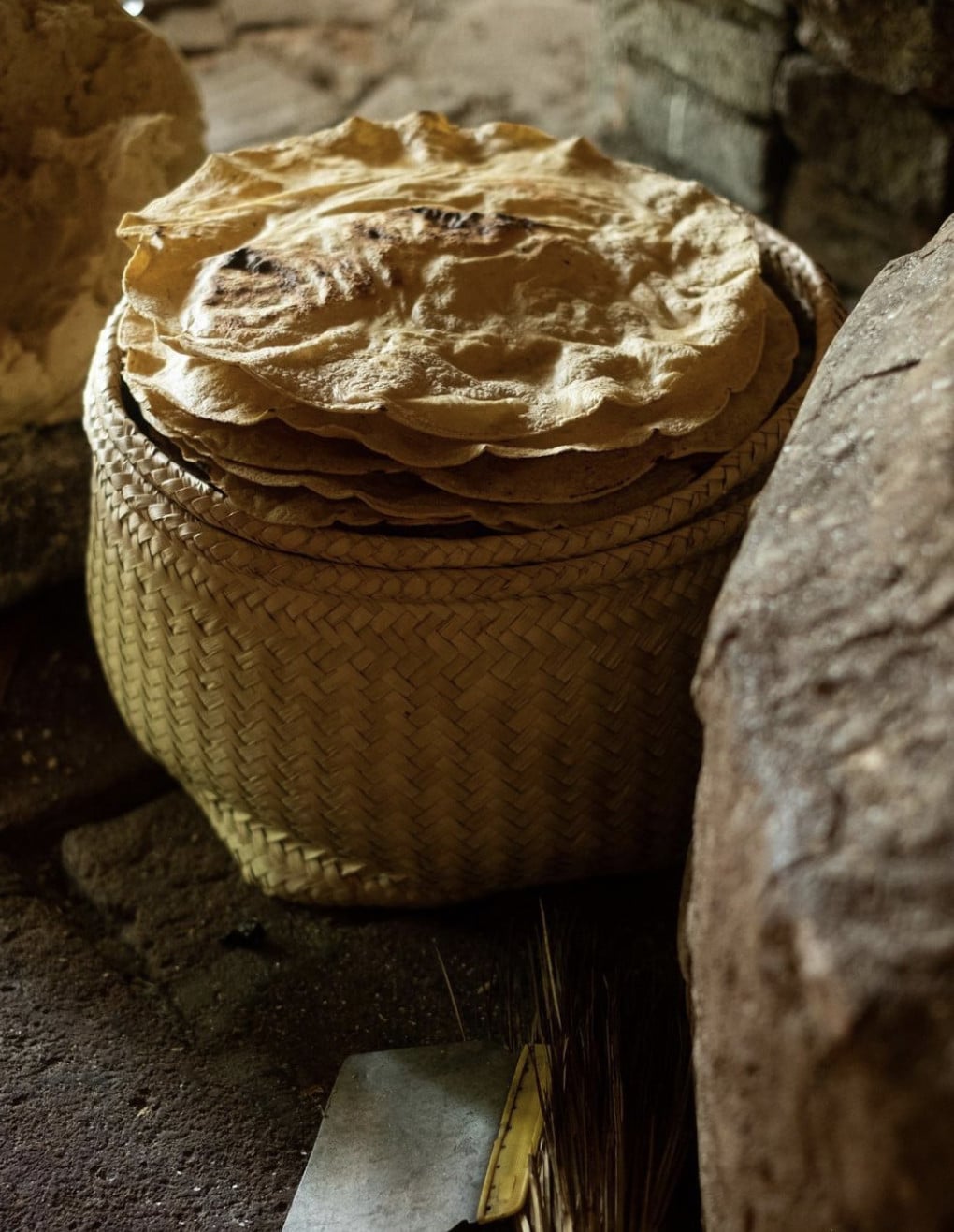 Alfonsina, Mexico — Woven basket with traditional lime plaster lid in rustic stone interior, artisanal Mexican hospitality detail.