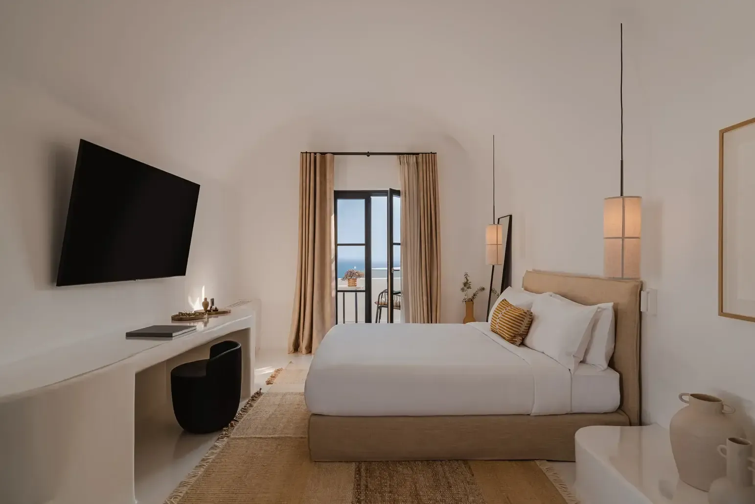 Nobu Santorini, Europe — Minimalist hotel bedroom with neutral tones, sea-view balcony, pendant lighting, and warm natural materials overlooking Aegean landscape.