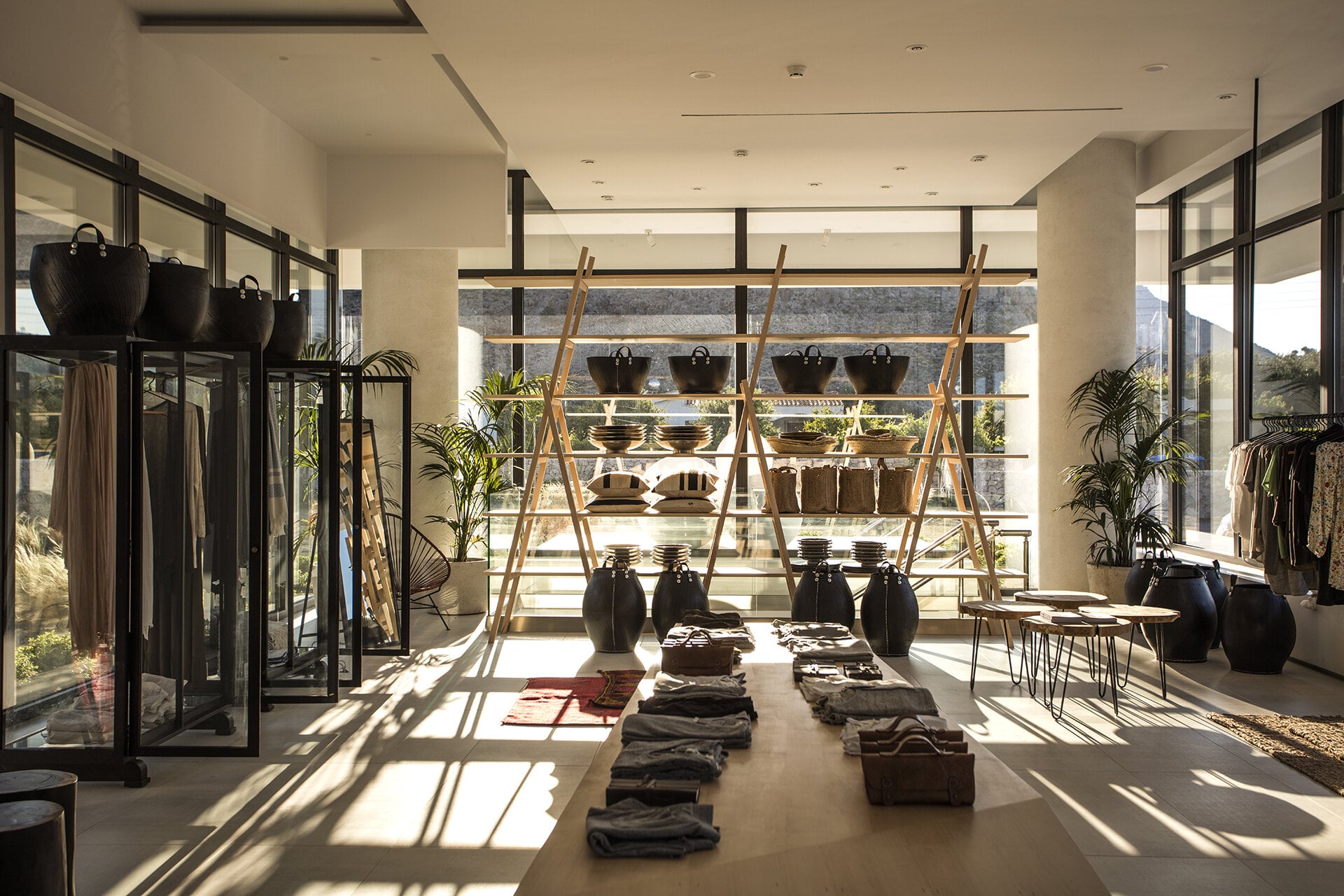 Casa Cook Rhodes, Rhodes, Greece — Minimalist retail space with natural light, wooden shelving, black leather accessories, neutral textiles, and contemporary design elements.