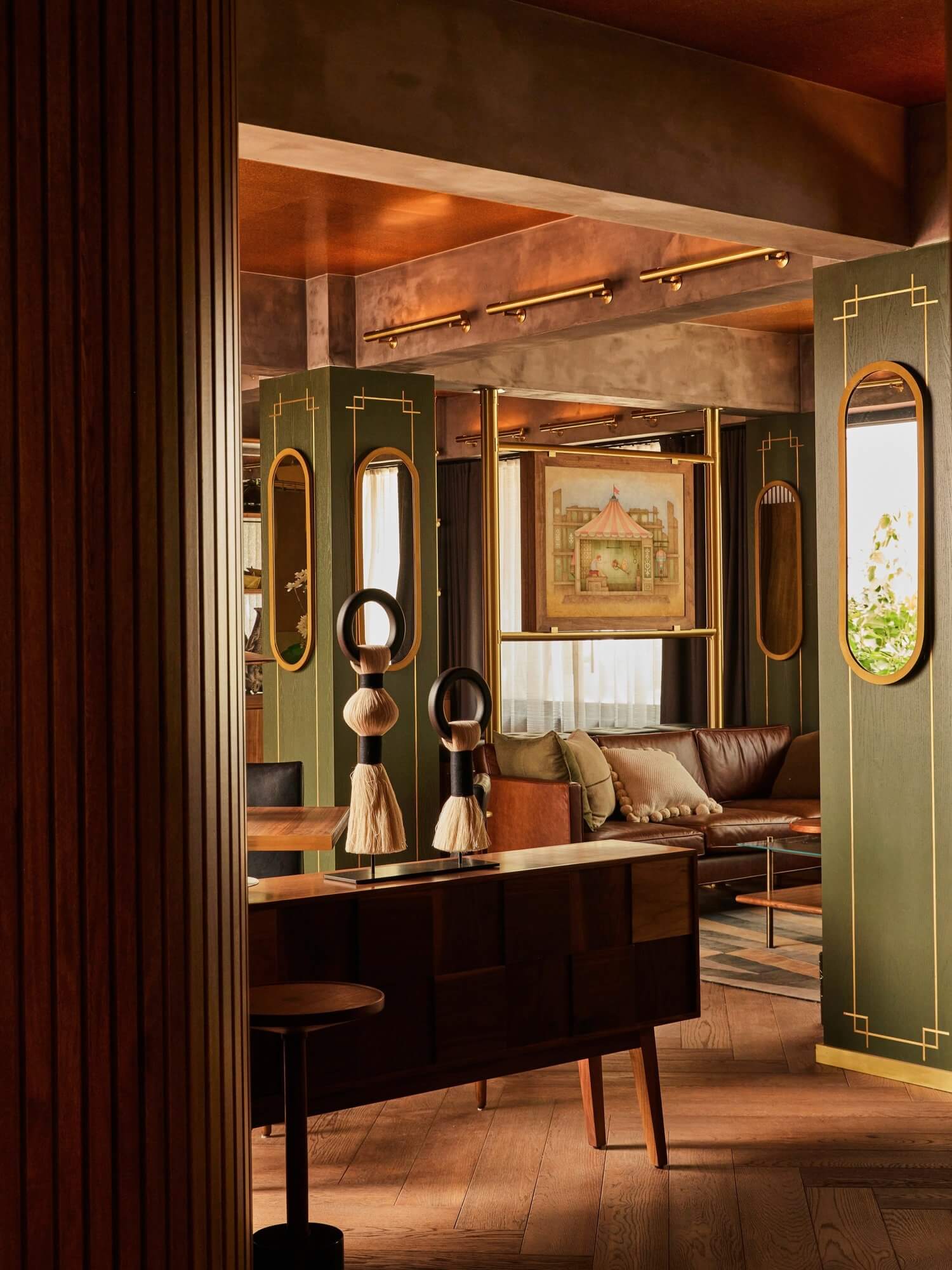 Campos Polanco, Mexico — Luxury hotel suite with sage-green cabinetry, brass-trimmed mirrors, leather seating, and warm ambient lighting creating an art deco-inspired interior.