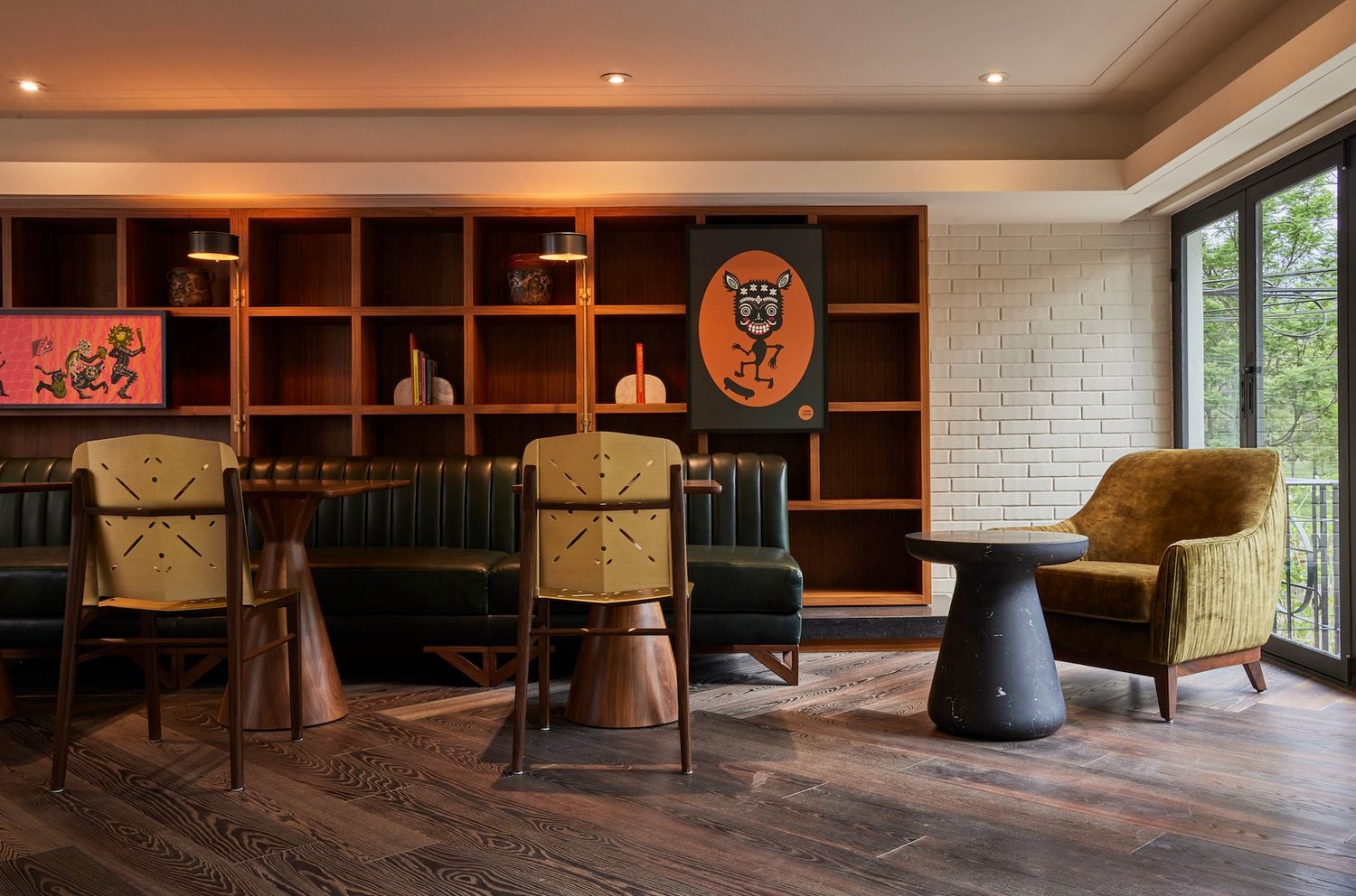 Campos Polanco, Mexico — Mid-century lounge with cognac leather banquette, wood shelving, geometric artwork, and floor-to-ceiling windows overlooking gardens.