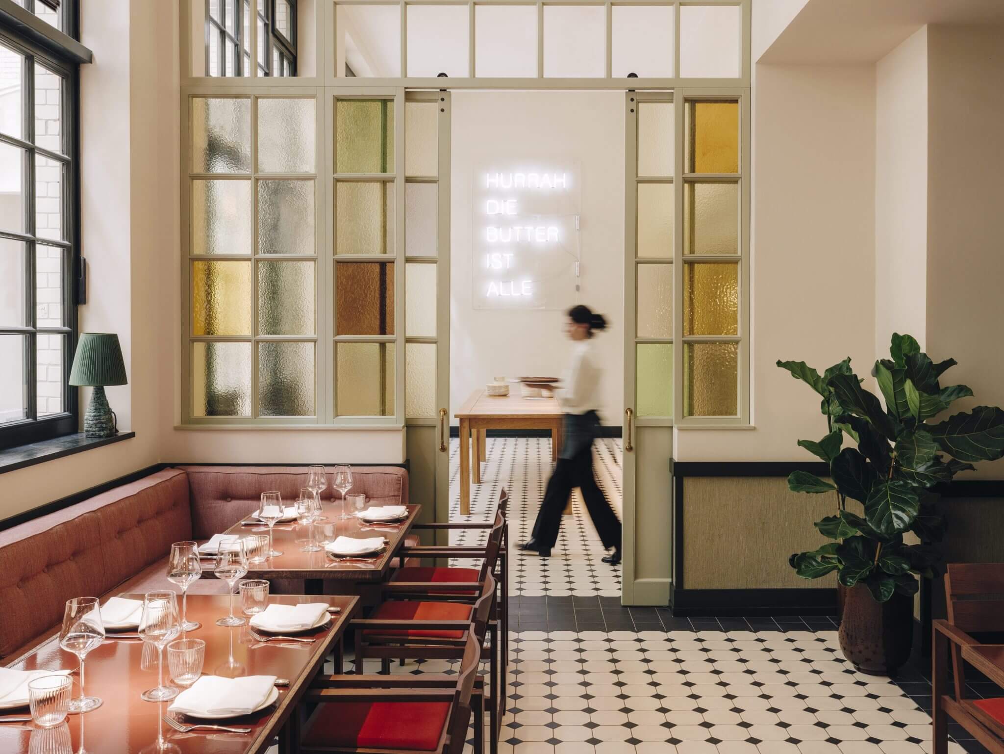 Château Royal, Europe — Mid-century dining room with terracotta banquettes, textured glass partitions, geometric floor tiles, and neon signage.