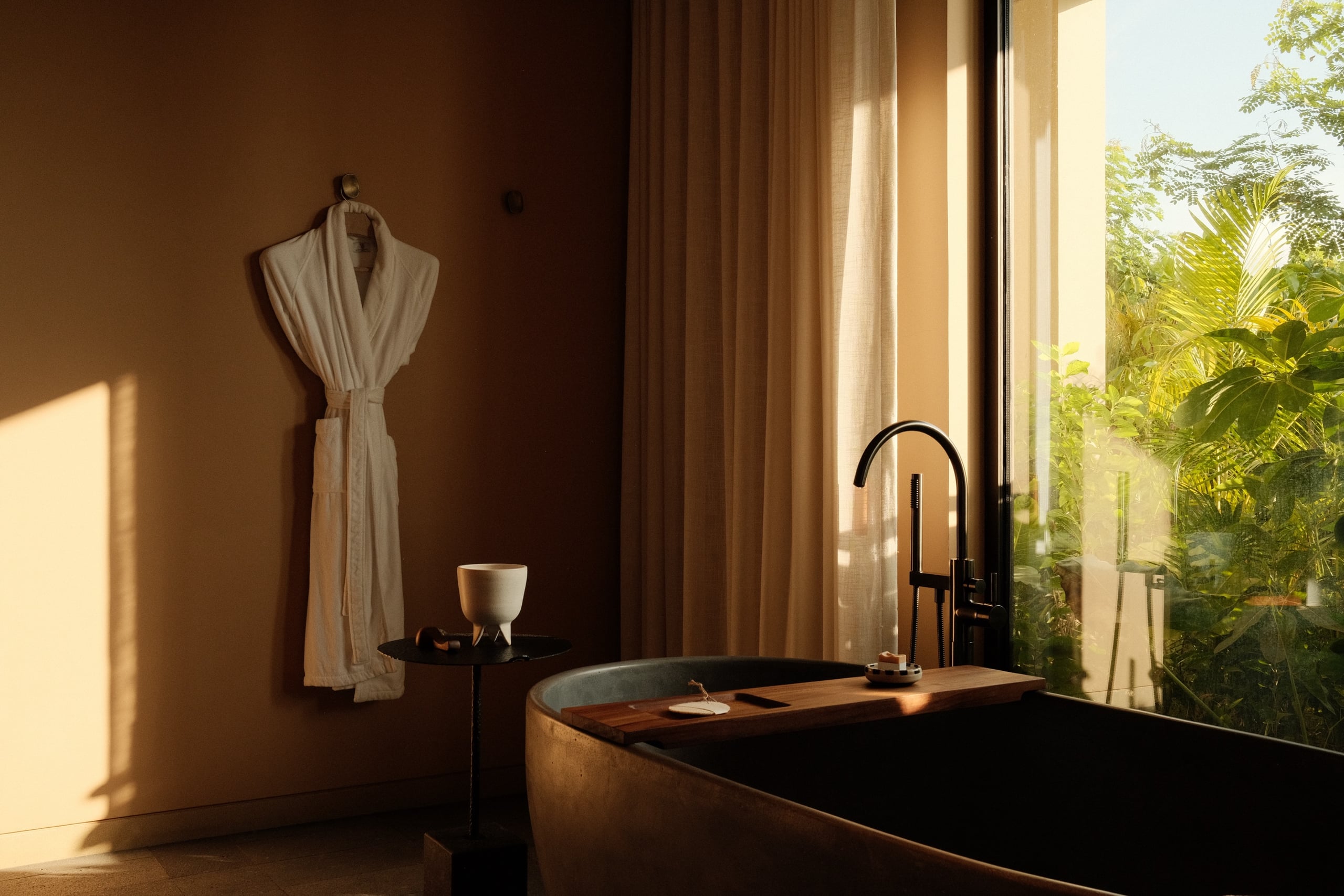 Rosewood Mandarina, Mexico — stone soaking tub and robe beside a jungle window, photographed by KOBU