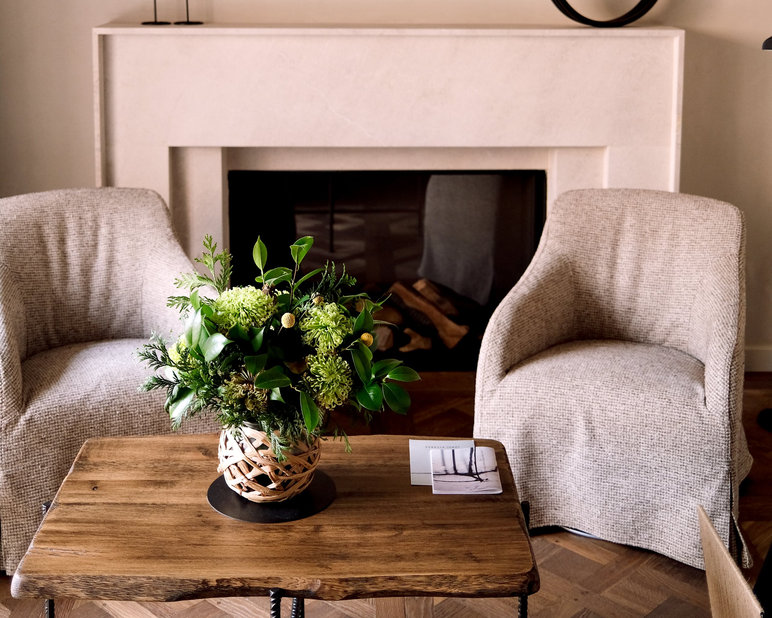 Can Ferrereta, Balearic Islands, Spain — Linen armchairs flank a reclaimed wood table with fresh greenery beside a pale stone fireplace.