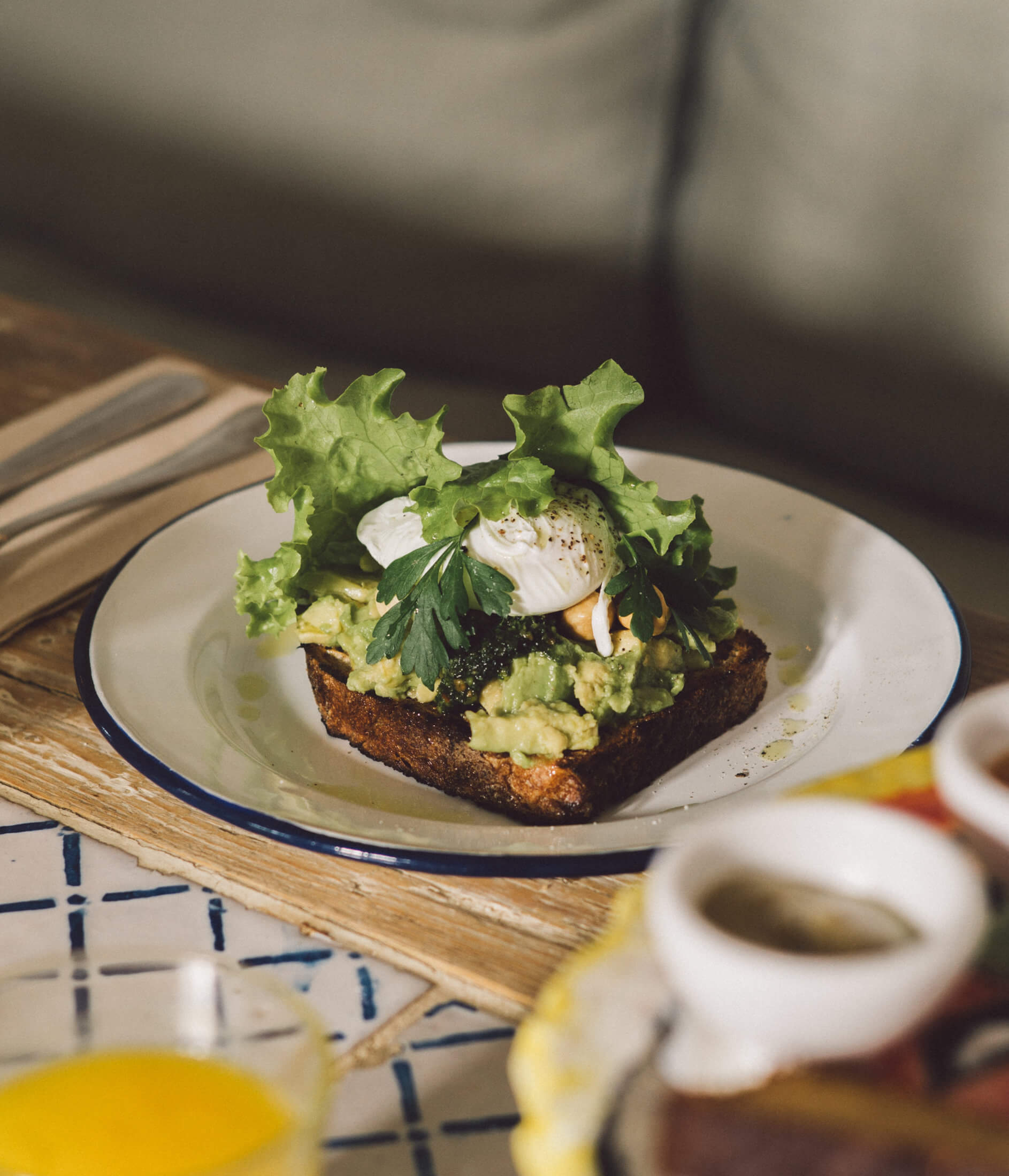 Villa Lena, Europe — Avocado toast with poached egg and microgreens on ceramic plate, natural light, minimalist table setting.