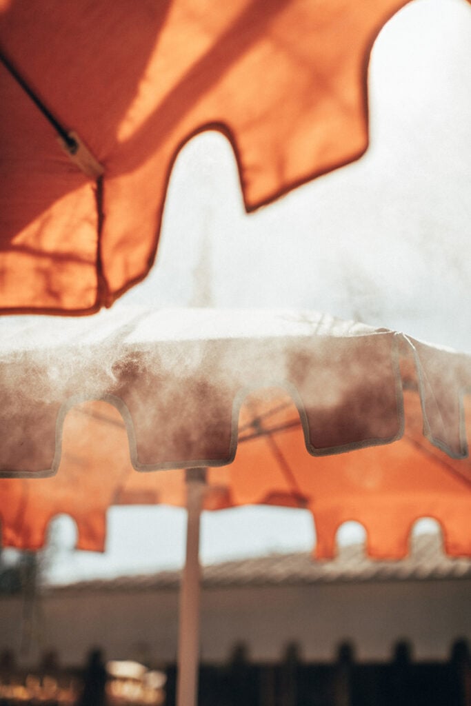 Epi 1959, Europe — Sheer white curtains filtering warm sunlight through orange fabric, creating layered shadows and soft diffused light in minimalist interior space.