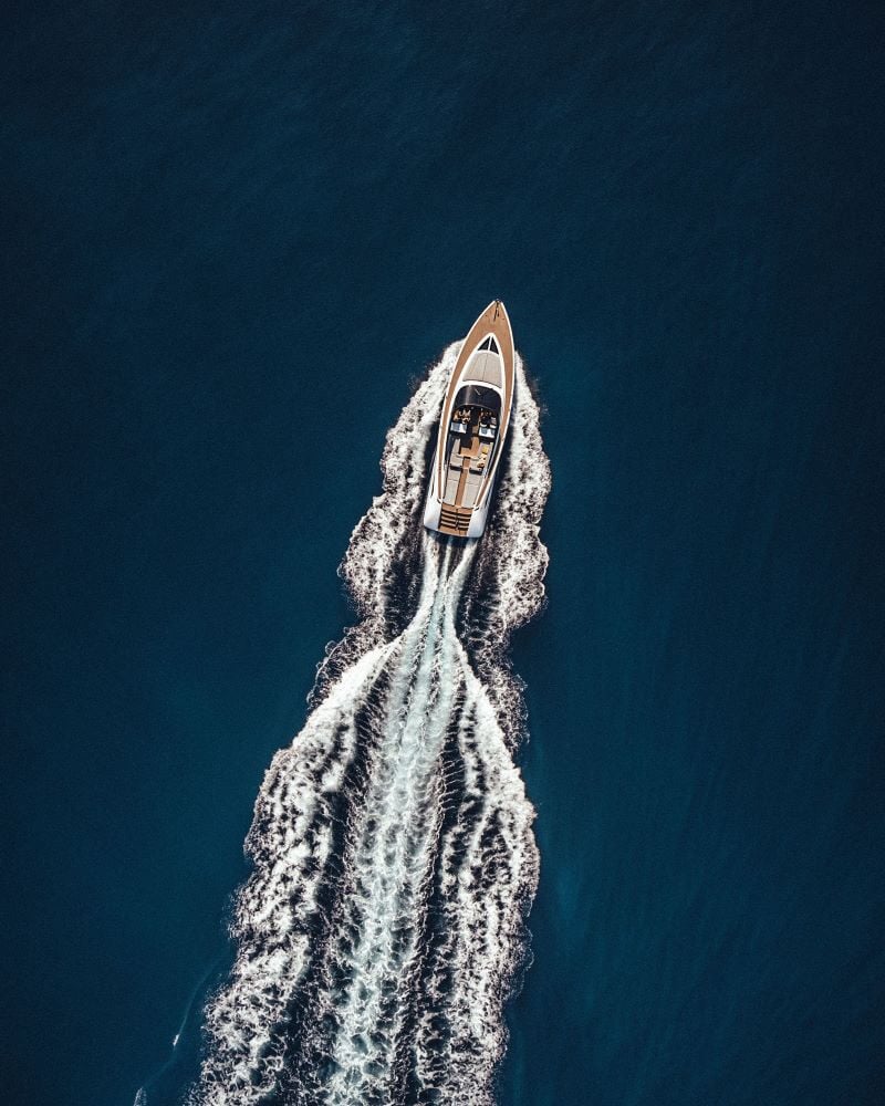 Epi 1959, Europe — Luxury yacht cutting through deep blue Mediterranean waters, aerial view capturing white wake trail and teak deck design.
