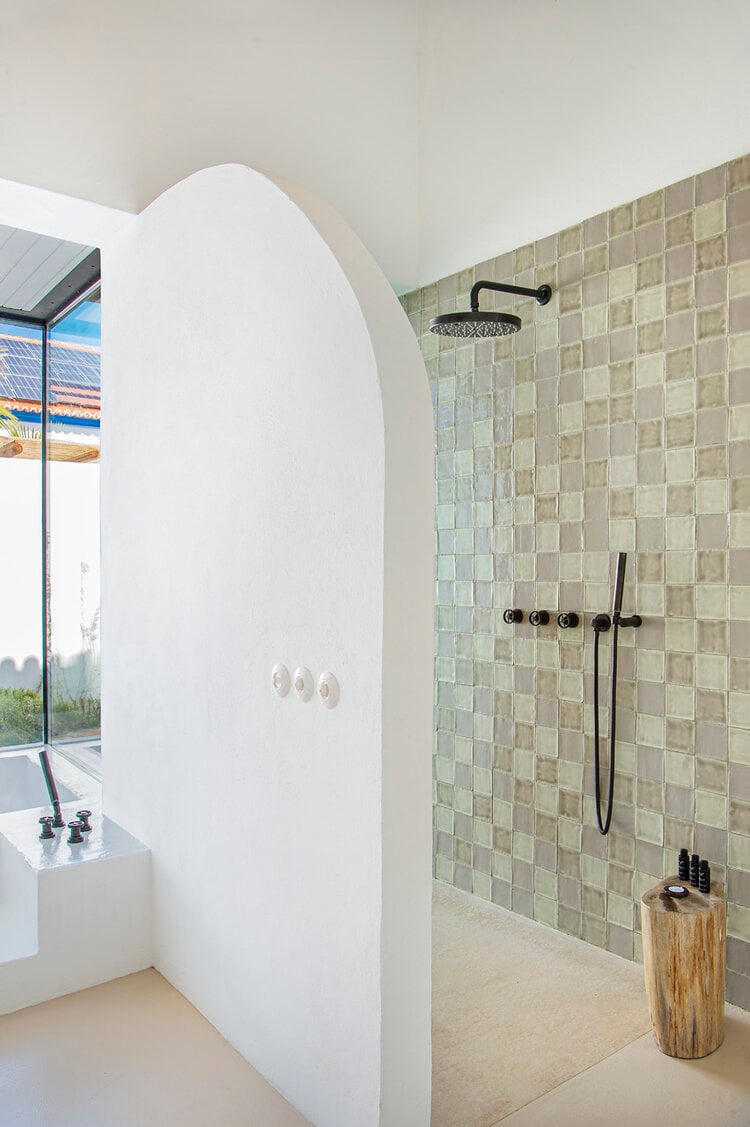 Quinta da Comporta, Europe — Minimalist bathroom with curved white partition wall, sage green tile shower, black fixtures, and natural light from expansive window.