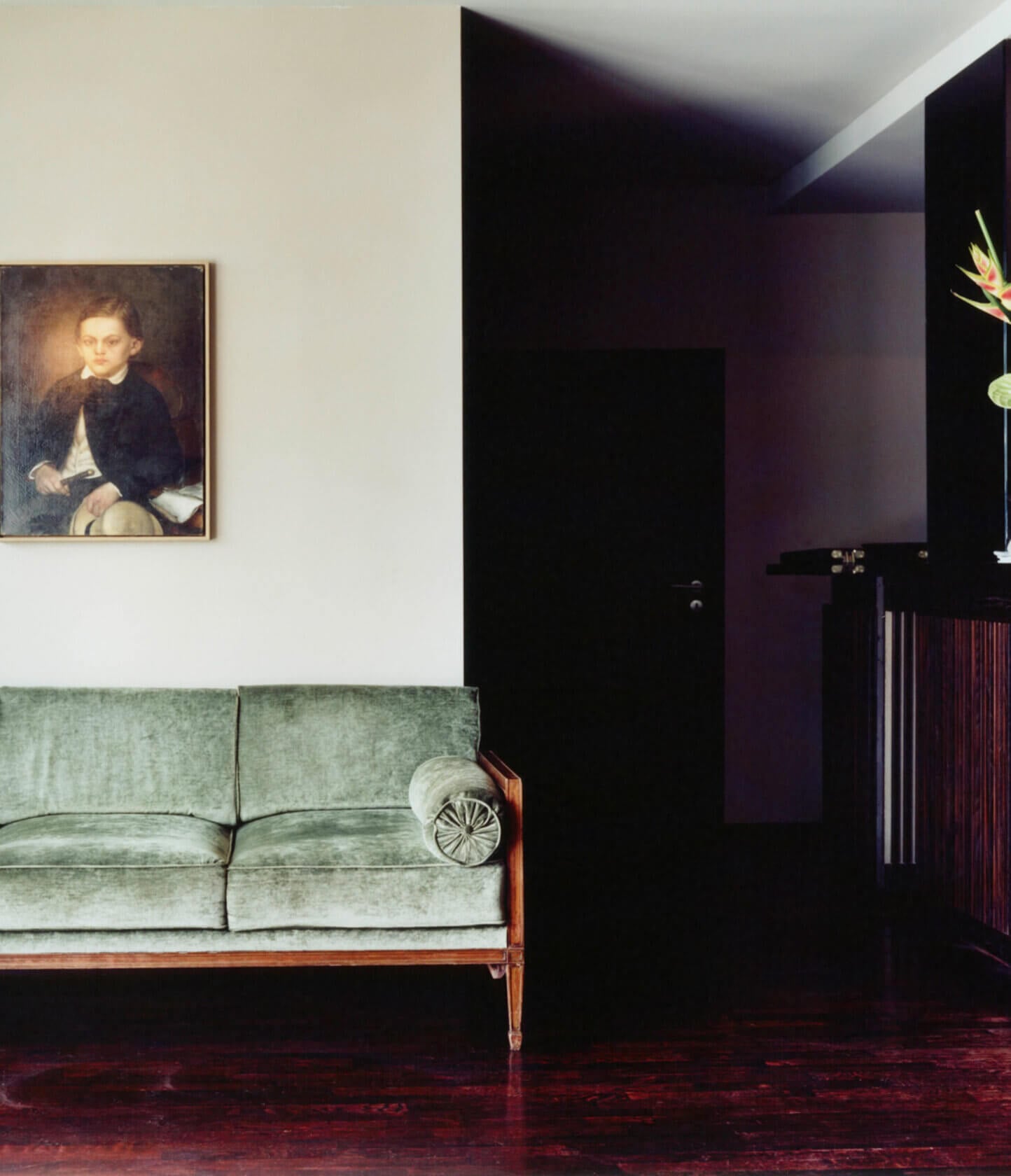 Grill Royal, Europe — Modernist living room with sage velvet sofa, burgundy terrazzo floor, black wall paneling, and classical portrait painting.