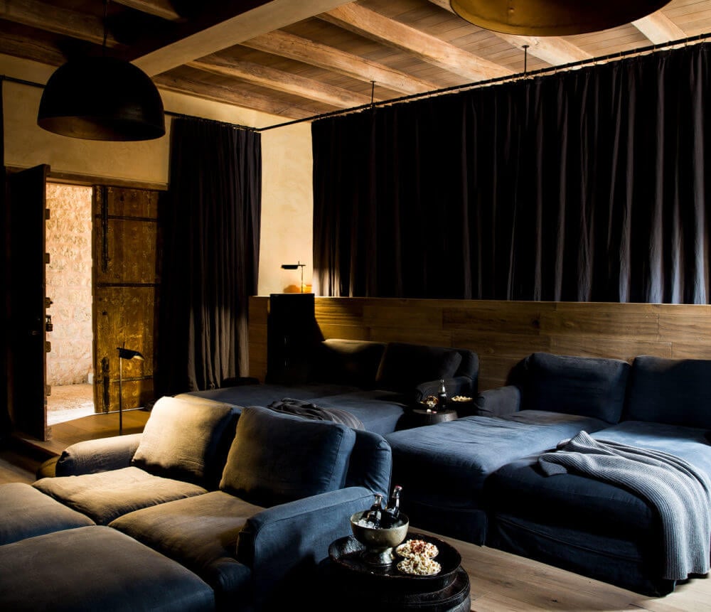 Arijiju Retreat, Africa — Dark linen seating arrangement with wooden headboard, black curtains, exposed ceiling beams, and warm ambient lighting in luxury villa bedroom.