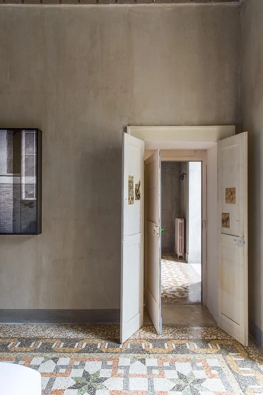 Palazzo Daniele, Europe — Double doors opening to terrazzo flooring in minimalist corridor with exposed plaster walls and natural light.
