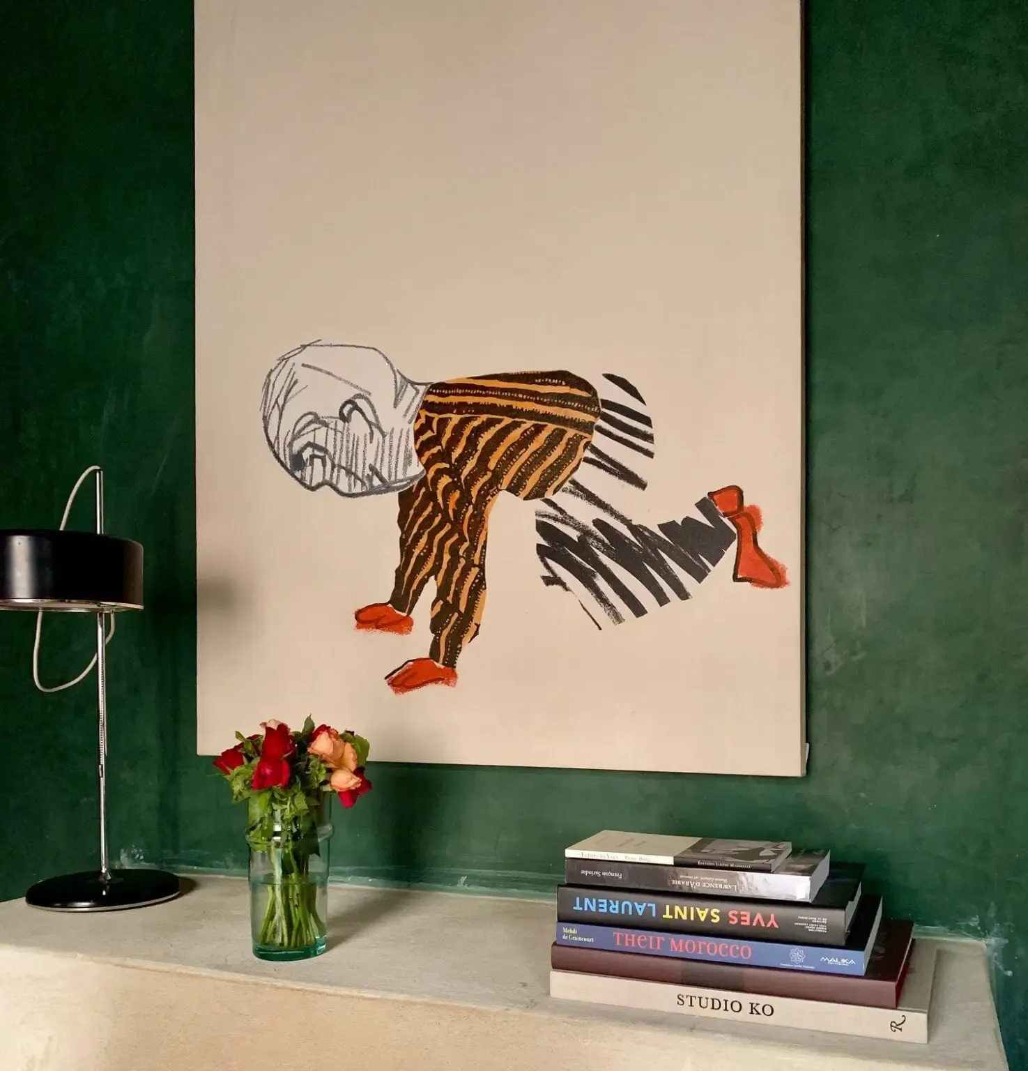 El Fenn, Marrakech, Morocco — Contemporary line art of contorted figure in striped ochre and black against cream wall, green gallery setting with books and fresh flowers.