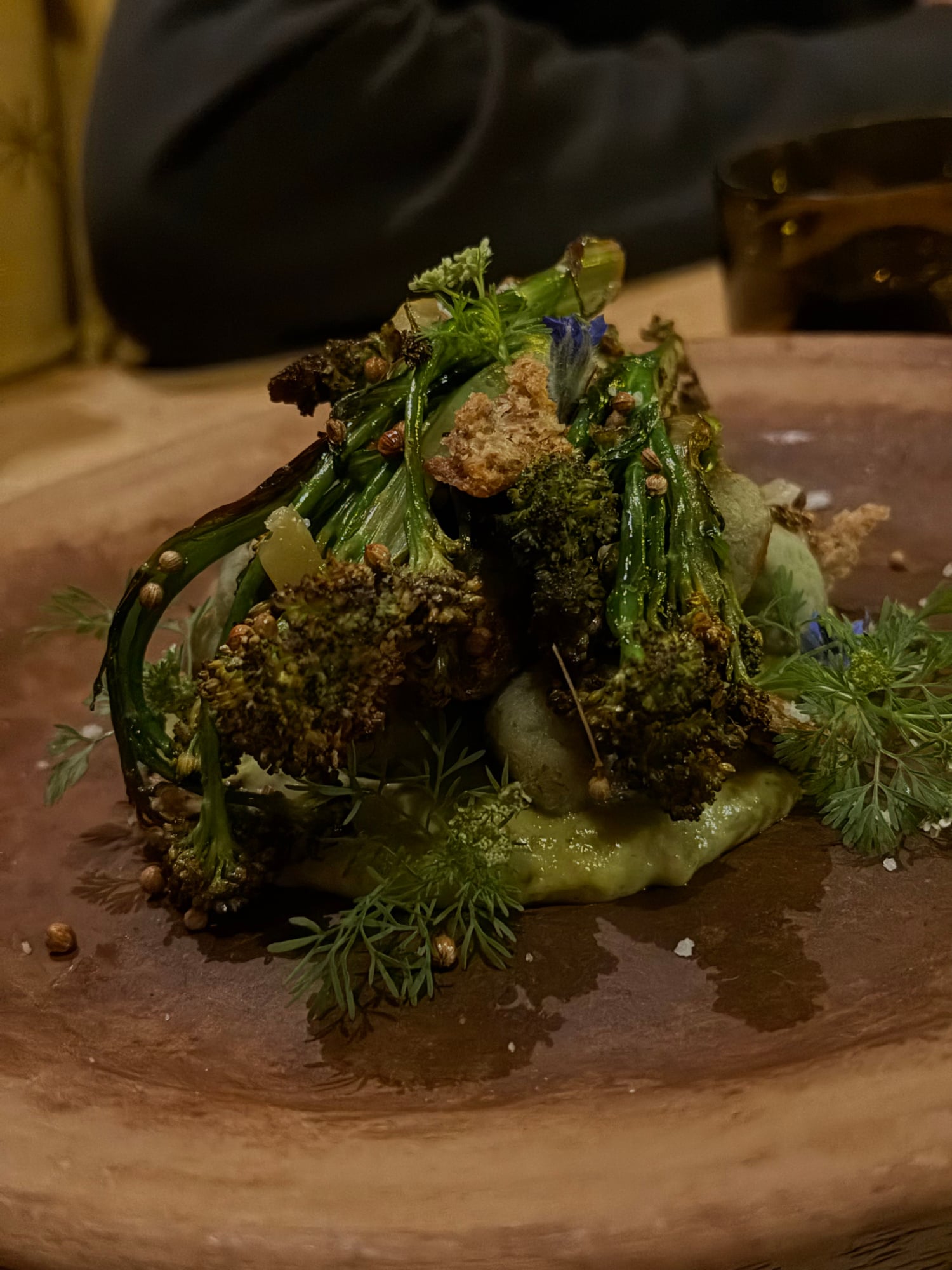 Artistic plating at Pahua with charred herbs, creamy sauce, and textured breadcrumbs on slate.