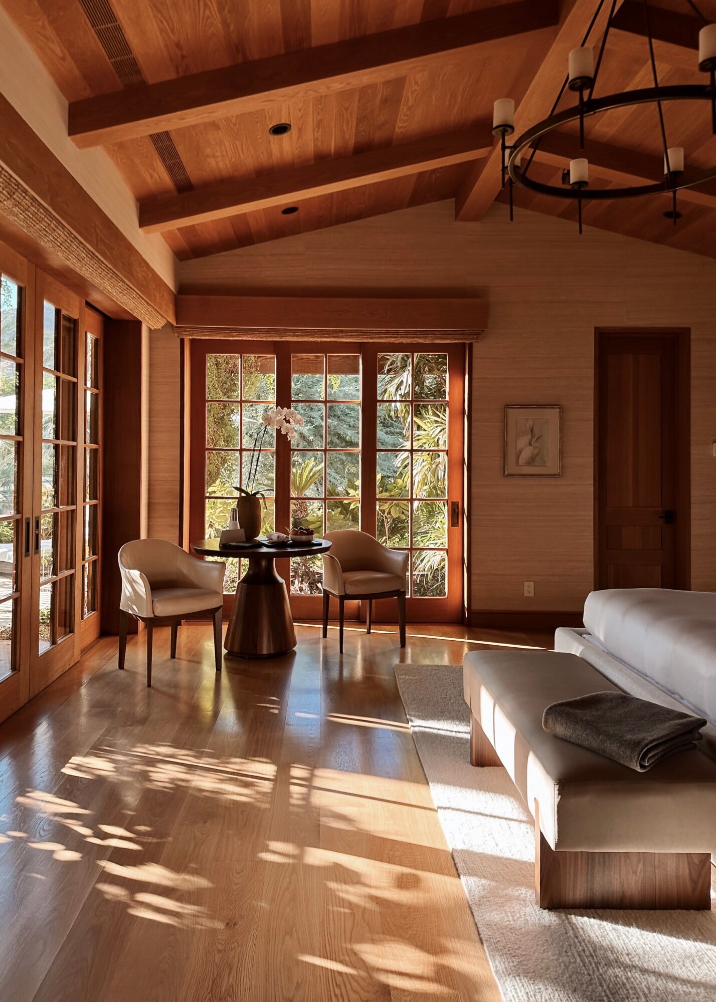 Sensei Porcupine Creek, North America — Wooden bedroom suite with exposed beam ceiling, floor-to-ceiling glazed doors, natural light, and minimalist furnishings overlooking garden landscape.