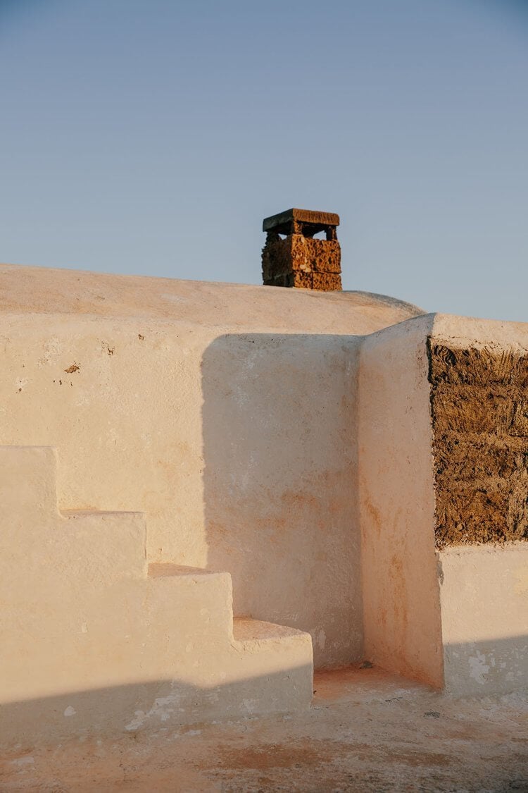 Parco Dei Sesi, Europe — Minimalist concrete staircase and archway carved into terracotta earth beneath clear sky, sculptural desert architecture.