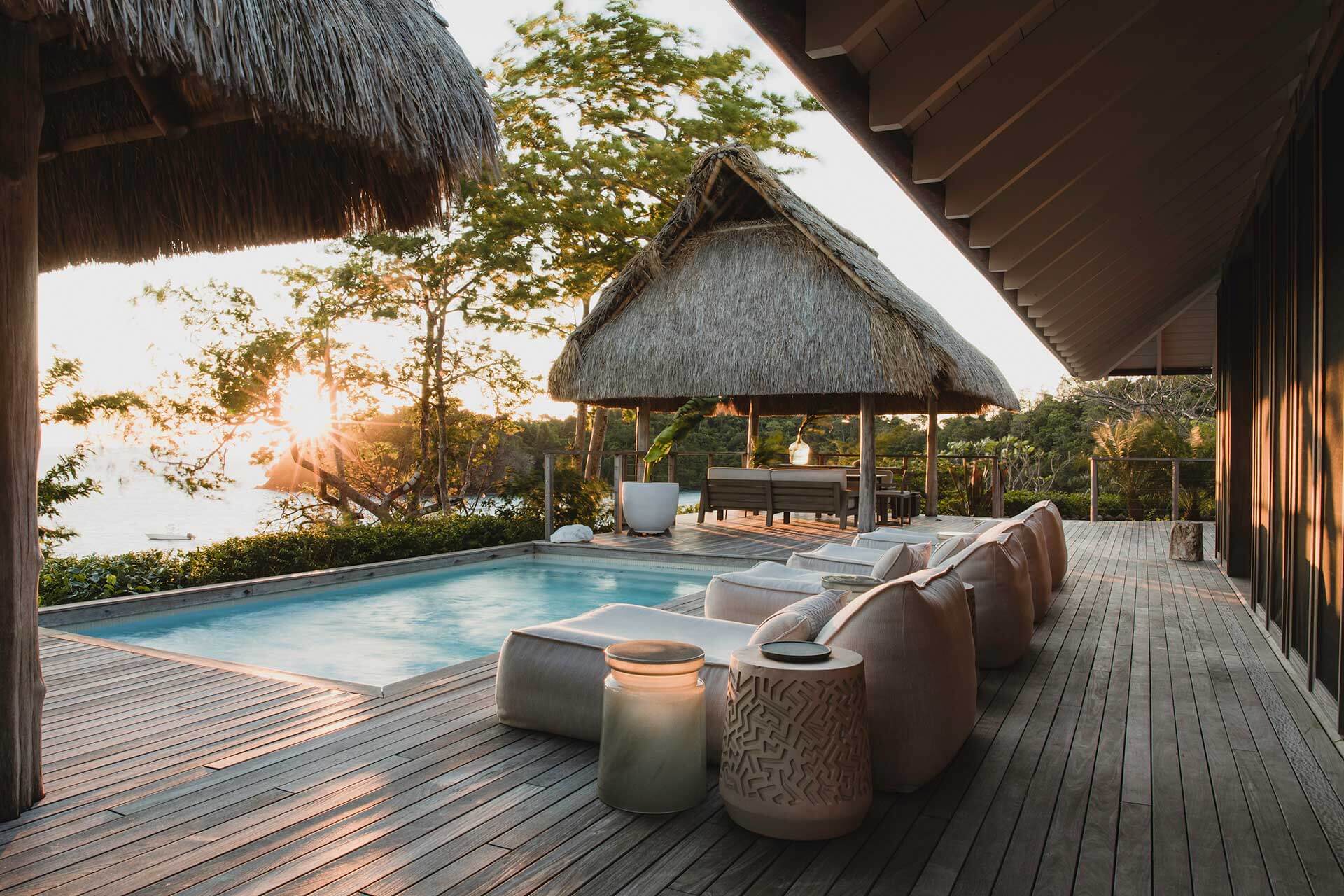 Islas Secas — Thatched-roof pavilion with infinity pool, teak deck, and sunset water views overlooking tropical landscape.