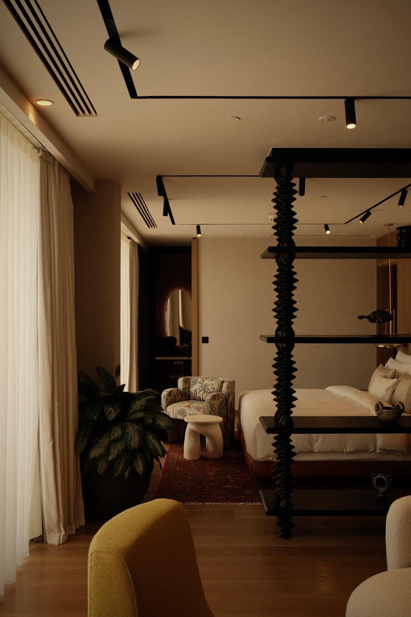 Aliée Istanbul, Istanbul, Turkey — Luxury hotel bedroom with sculptural black spiral column, canopy bed, warm lighting, and contemporary furnishings in neutral tones.