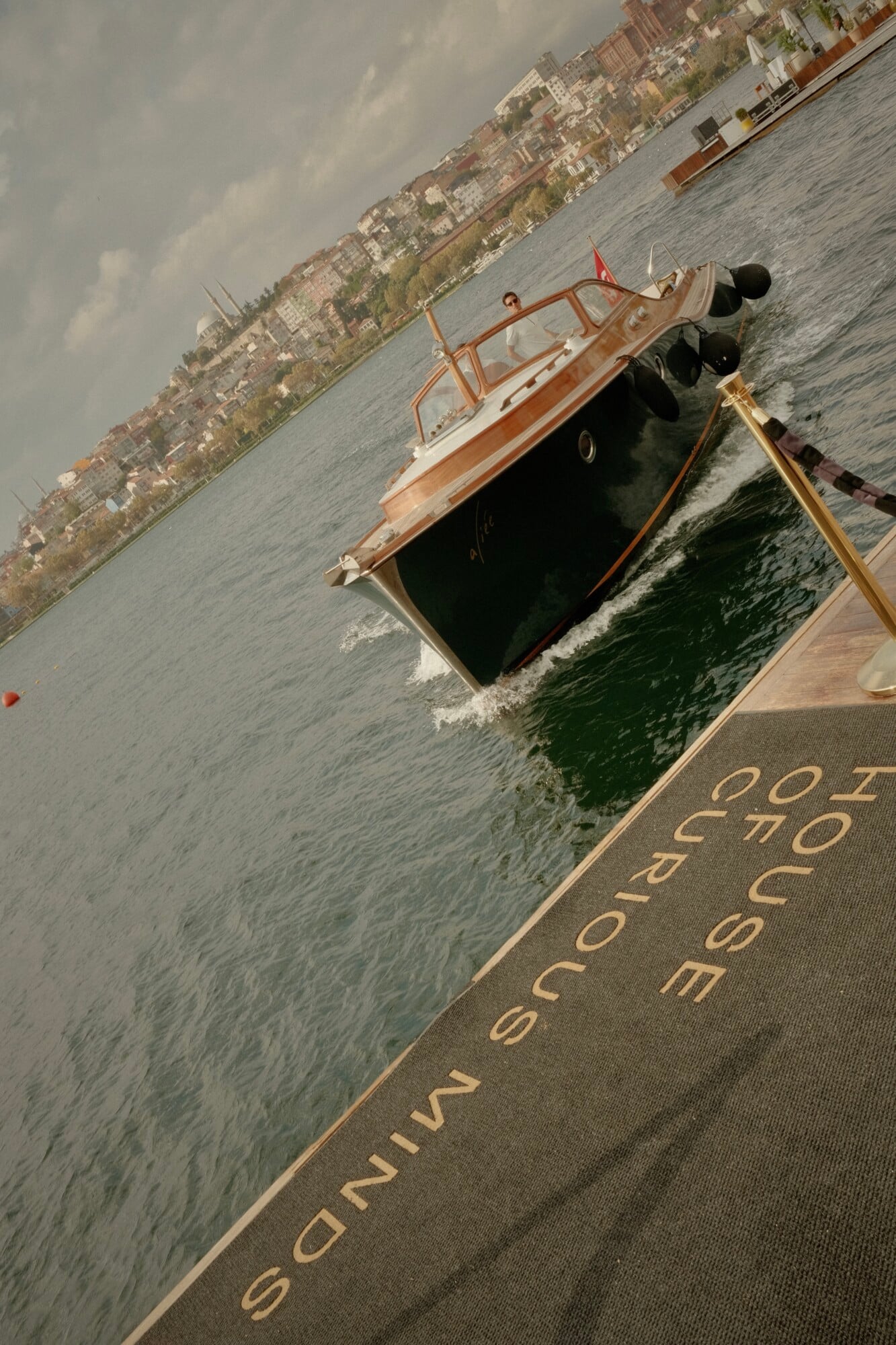 Aliée Istanbul, Istanbul, Turkey — wooden motor yacht with cream and mahogany hull moored at waterfront, Bosphorus cityscape beyond, afternoon light.