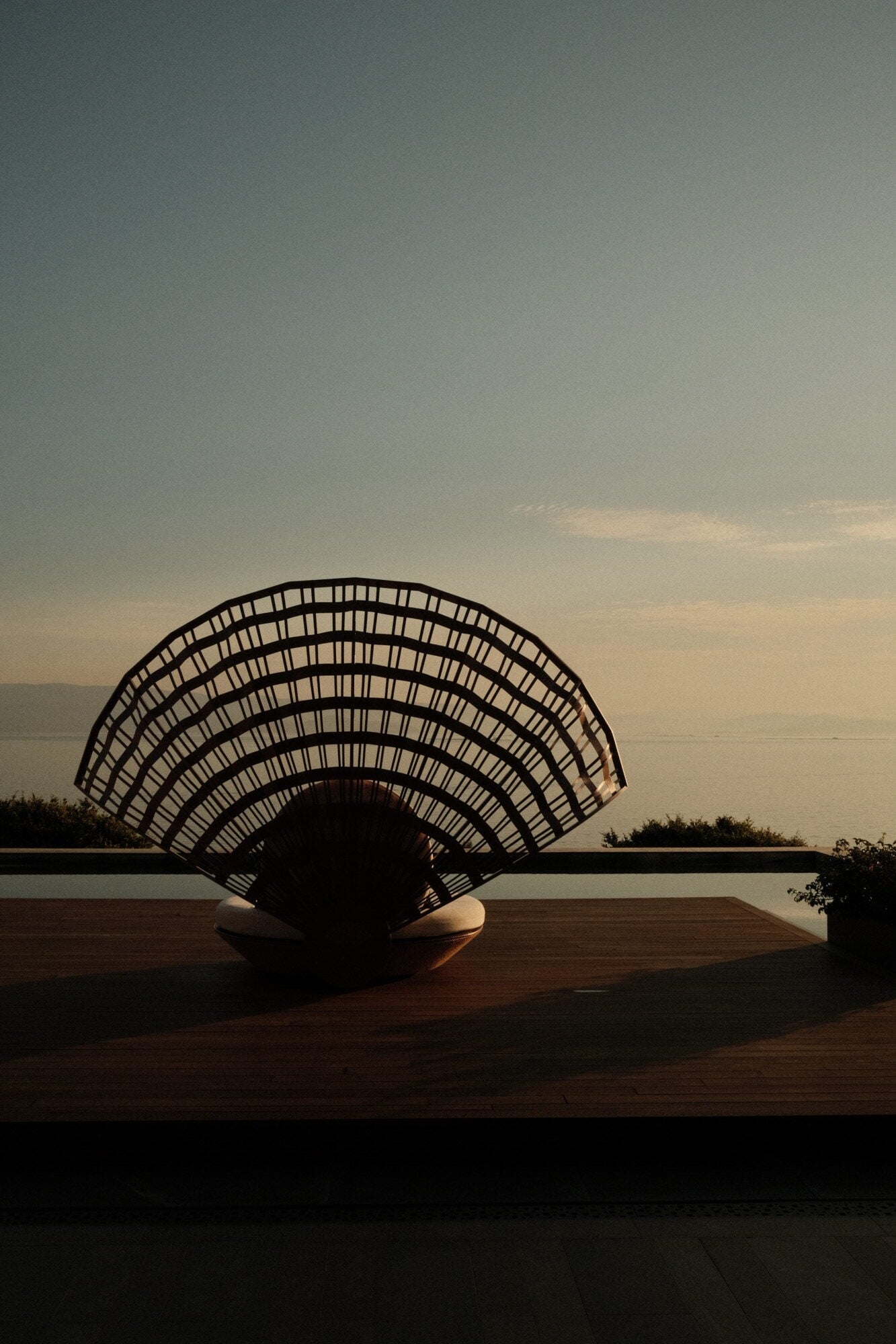 Mandarin Oriental Bodrum, Asia — Sculptural fan-shaped wooden pavilion silhouetted against golden sunset over water, architectural shade structure on terrace.