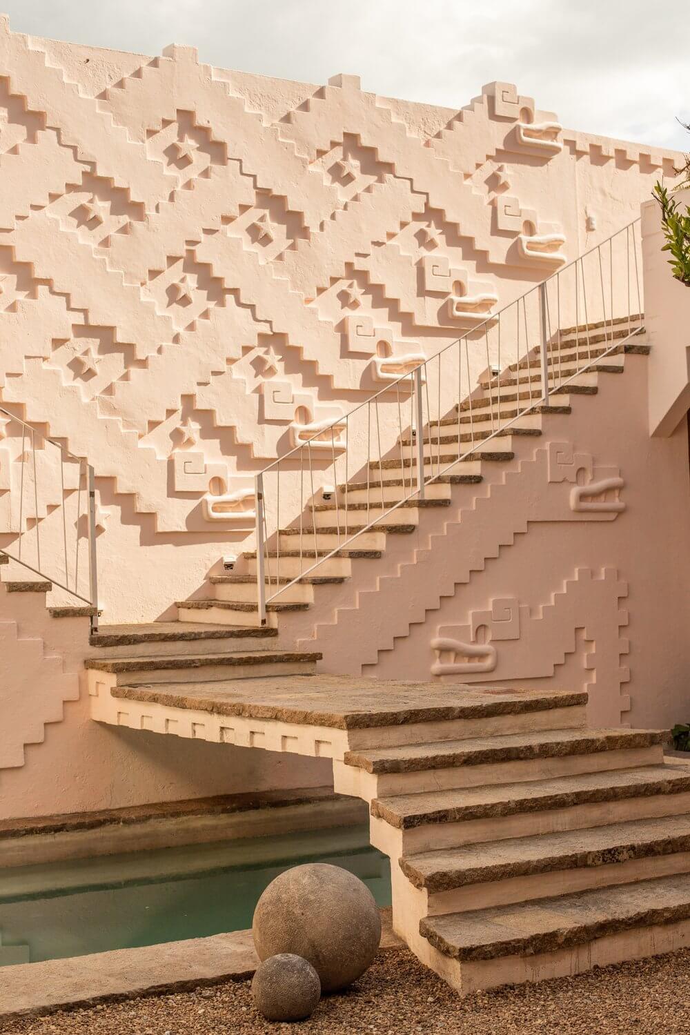 La Valise San Miguel, Mexico — Geometric terracotta façade with cascading stairs, metal railings, and reflecting pool beneath overcast sky.