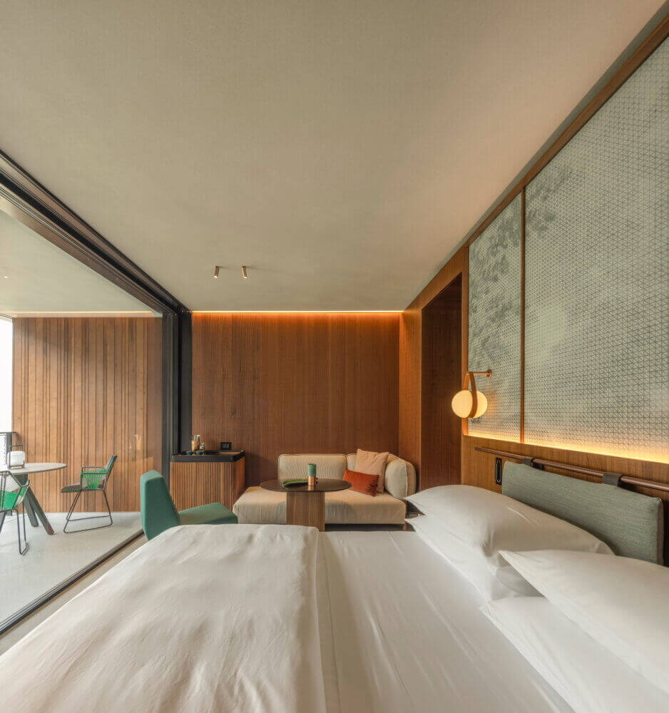 il Sereno Lago di Como, Italy — Minimalist hotel suite with paired beds, wood-paneled walls, floating pendant light, and floor-to-ceiling windows overlooking lake.