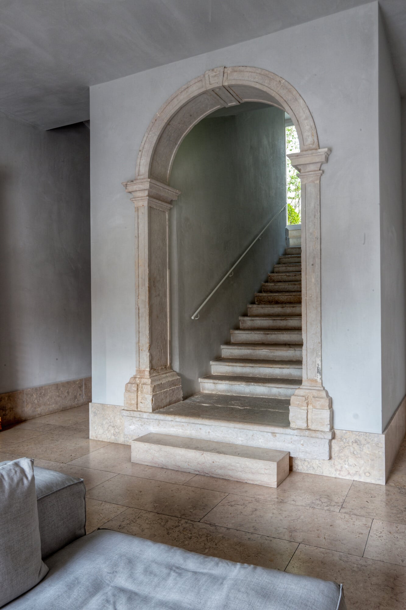 Santa Clara 1728, Portugal — Arched stone portal with classical columns framing sunlit staircase, minimalist interior architecture in neutral tones.